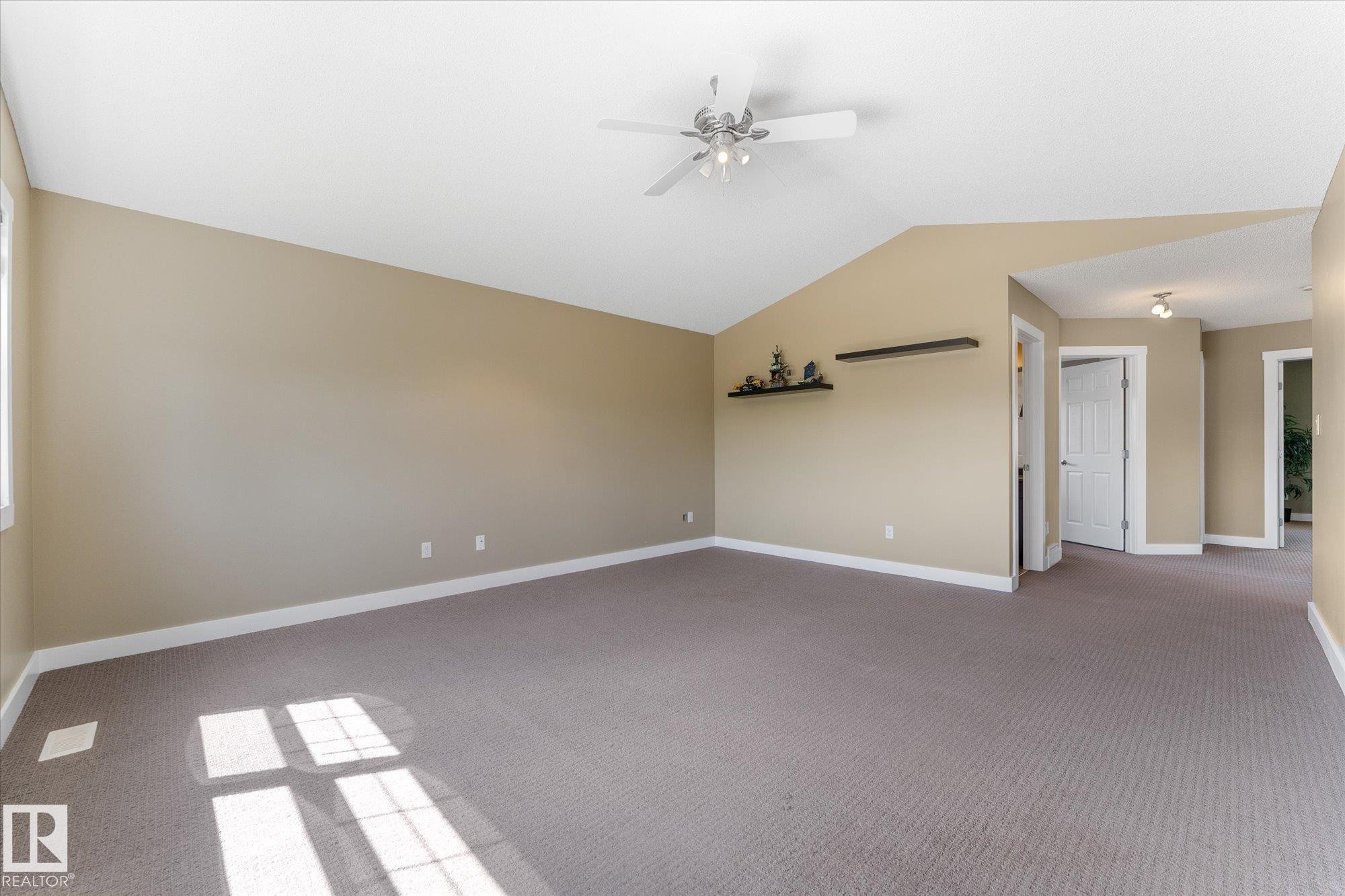 Spacious room featuring vaulted ceilings, a ceiling fan with integrated lighting, carpeted flooring, and neutral wall tones - 488 Macewan Road, Edmonton, AB
