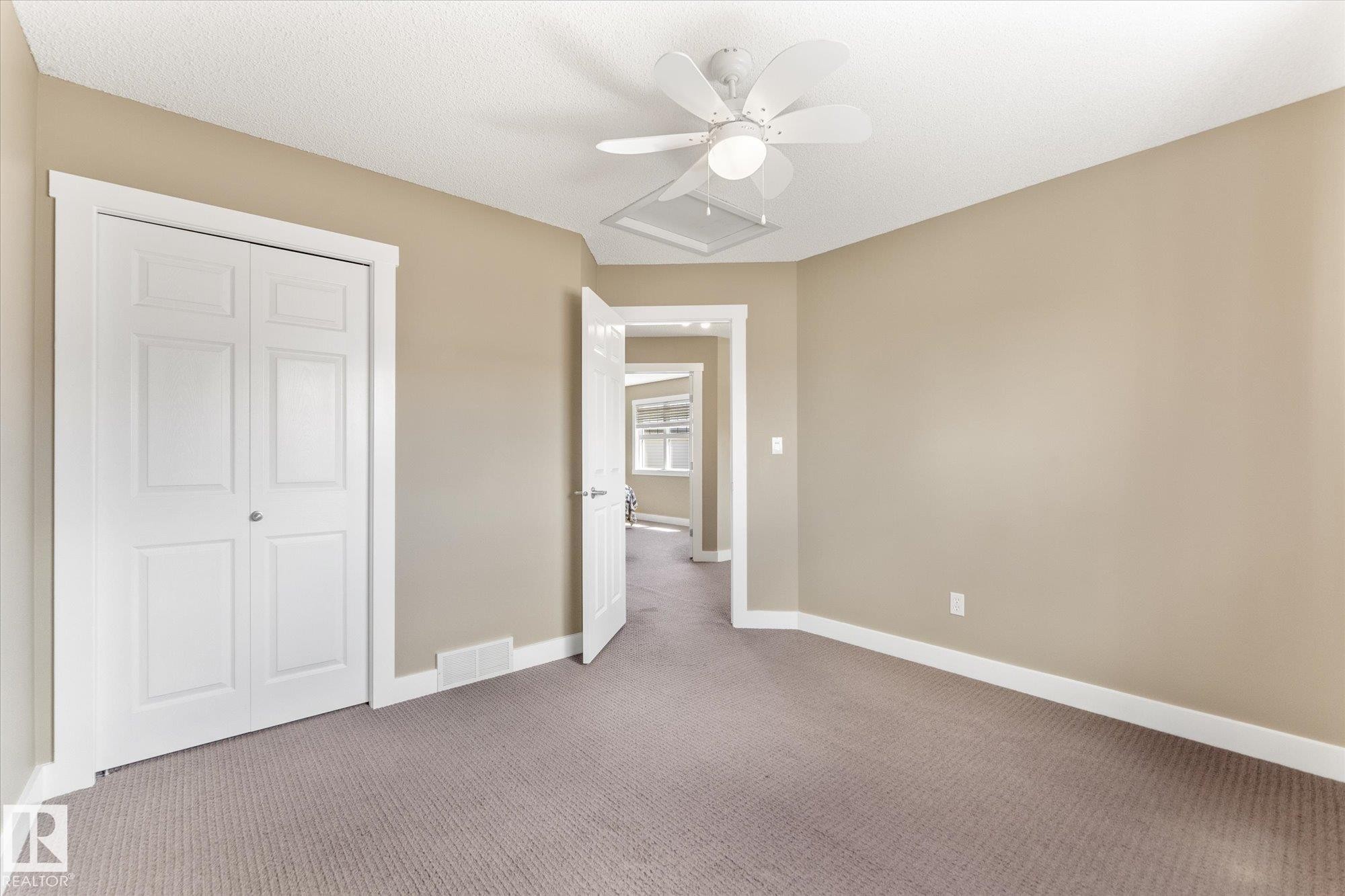 Room featuring neutral wall tones, textured carpeting, and white trim - 488 Macewan Road, Edmonton, AB