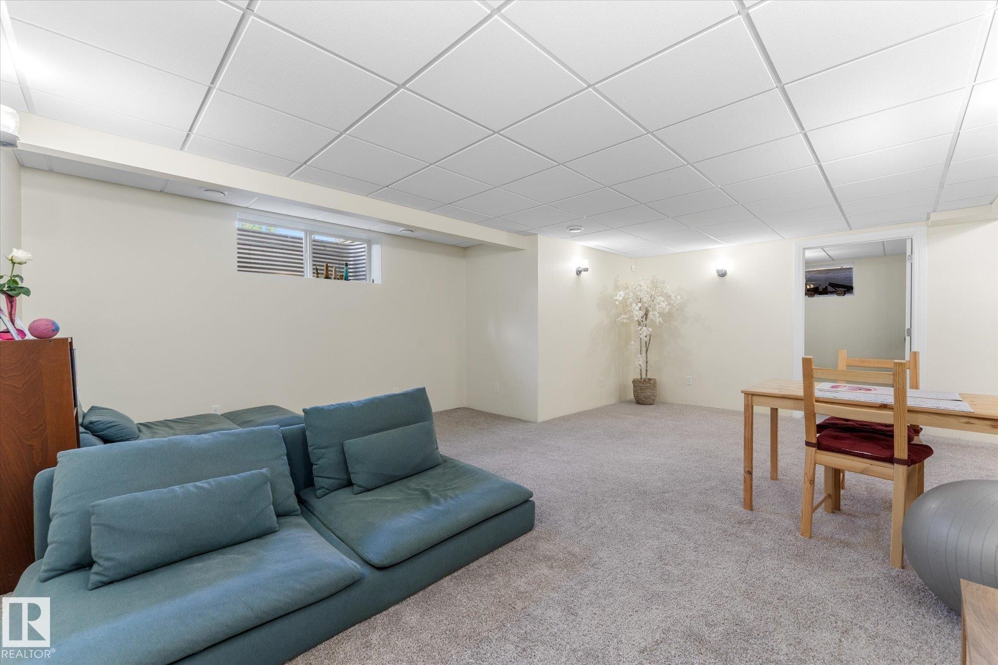 Spacious carpeted room featuring a white grid ceiling, light-colored walls, and a window with blinds - 488 Macewan Road, Edmonton, AB