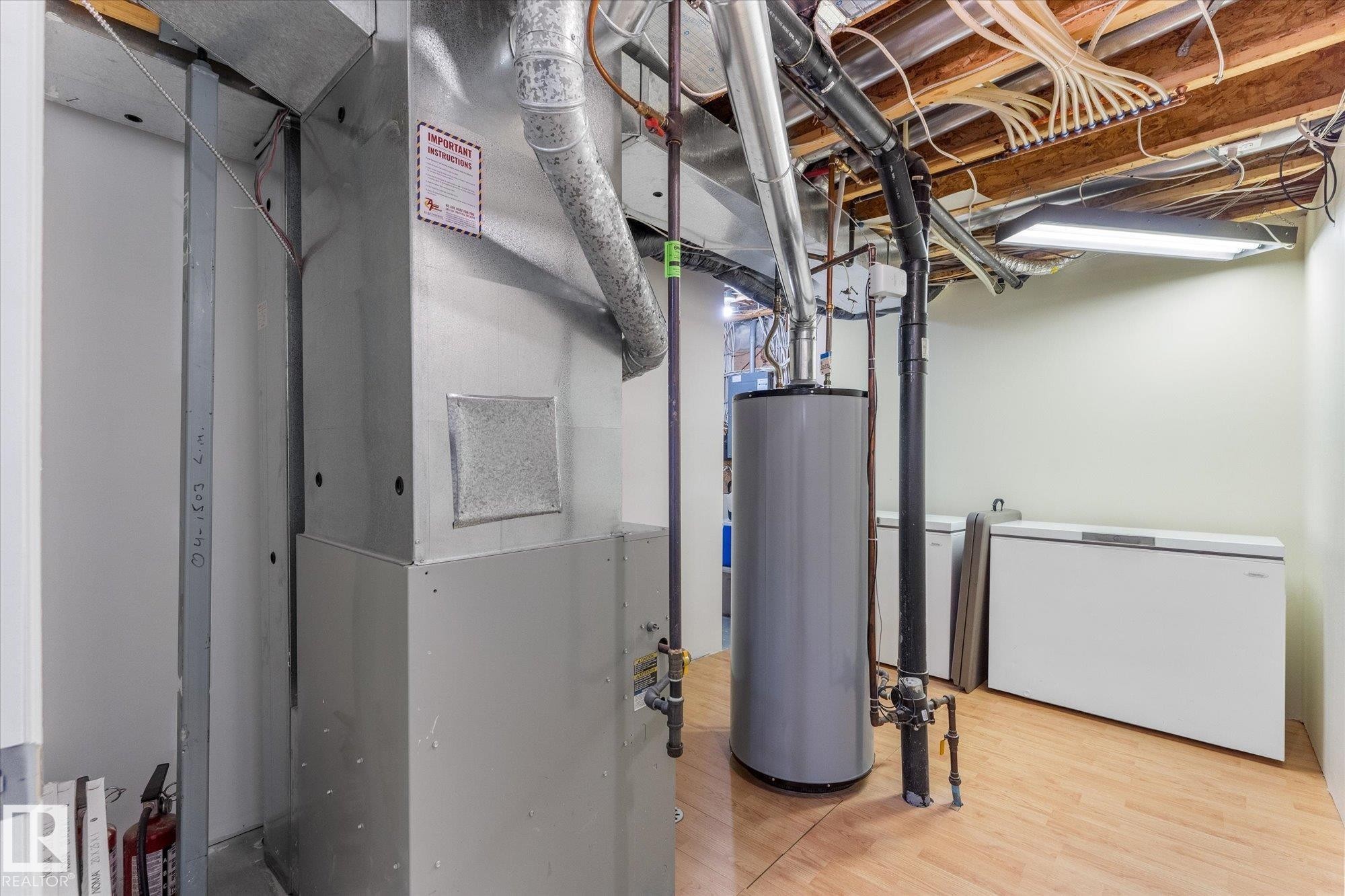 Utility room featuring mechanical systems, wood-finish flooring, and exposed ceiling joists - 488 Macewan Road, Edmonton, AB