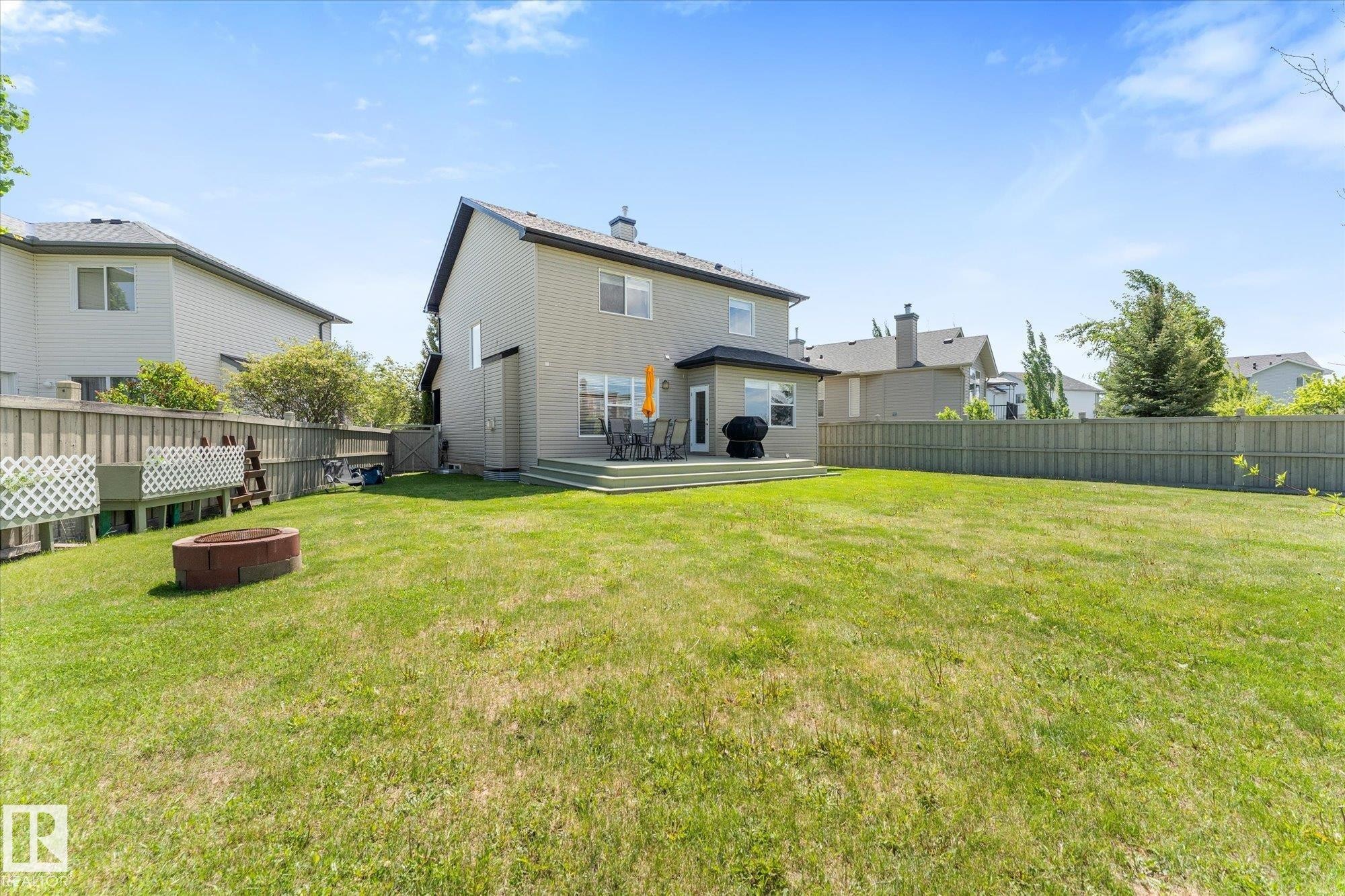 Expansive rear yard featuring a large green space, a multi-level wood deck, and a fire pit - 488 Macewan Road, Edmonton, AB