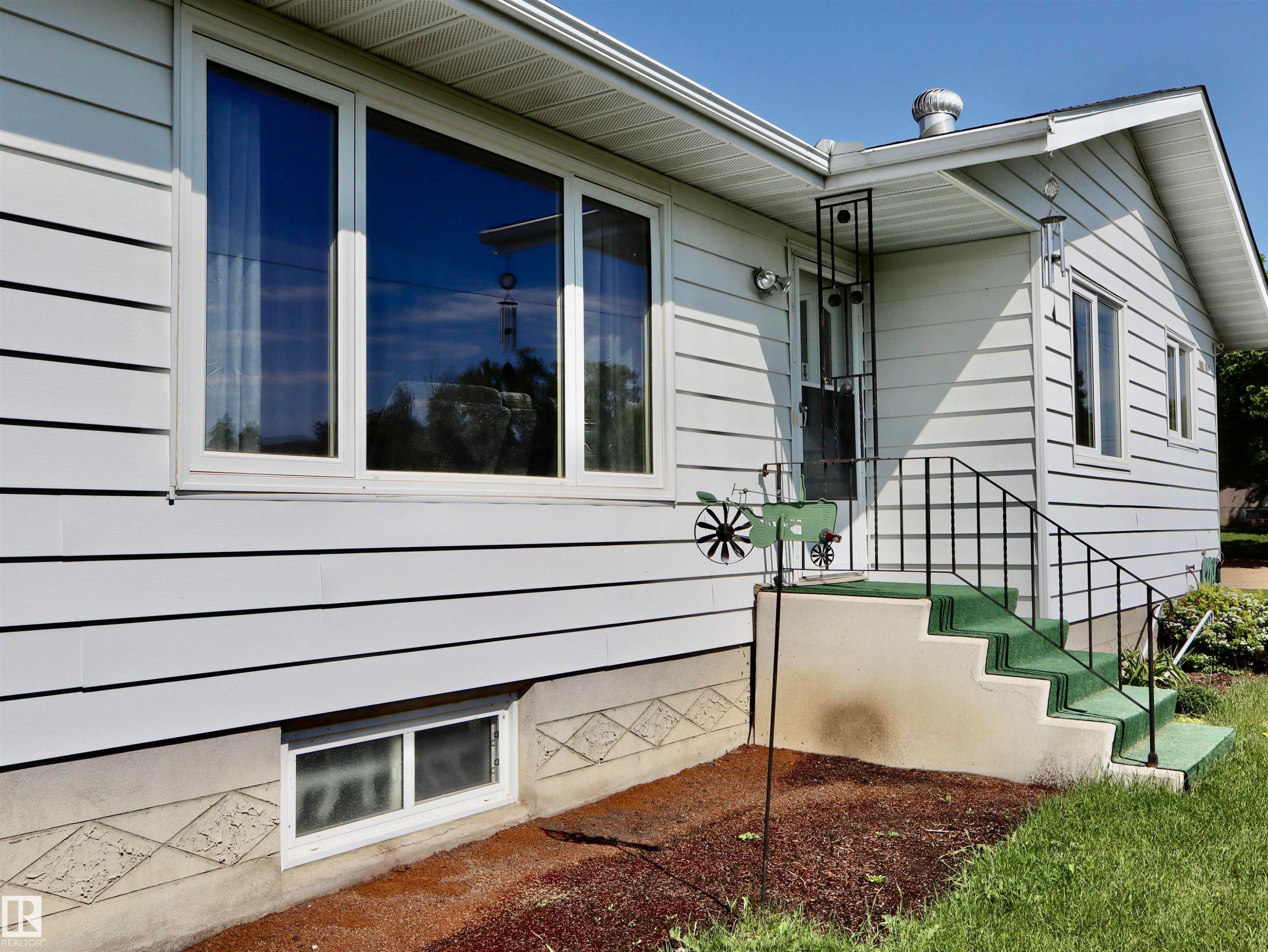 White horizontal siding exterior with multiple windows - 5530 46 Street, Barrhead, AB