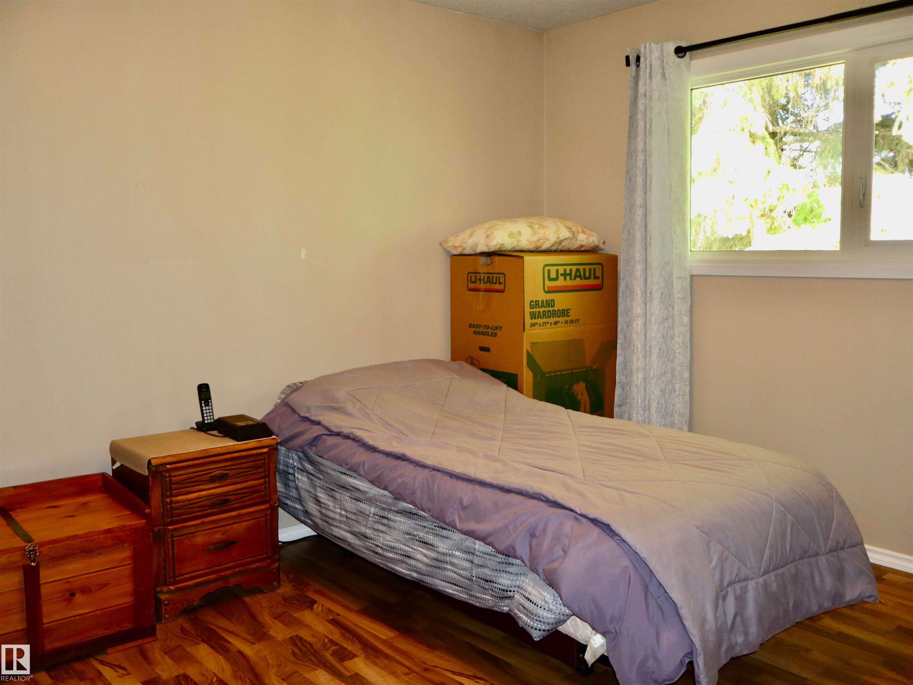 Room featuring wood-finish flooring, a double-pane window with white trim, and light neutral wall paint - 5530 46 Street, Barrhead, AB