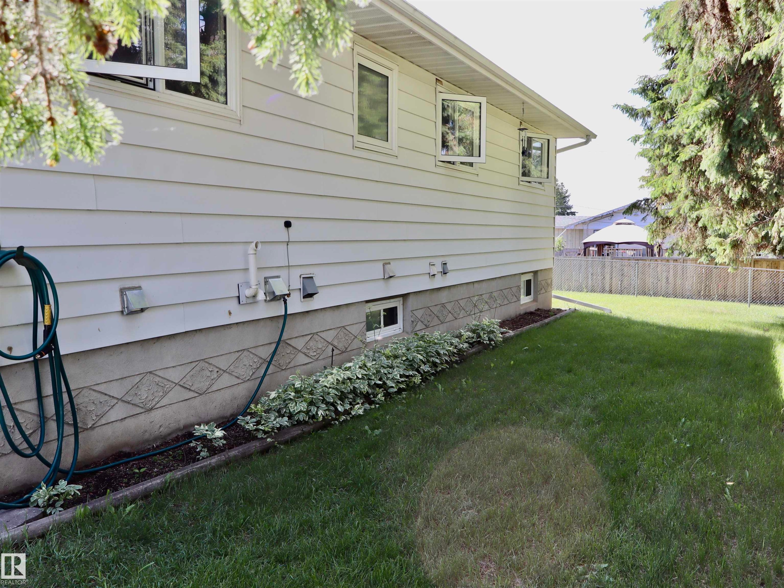 White horizontal siding exterior with a patterned concrete foundation - 5530 46 Street, Barrhead, AB