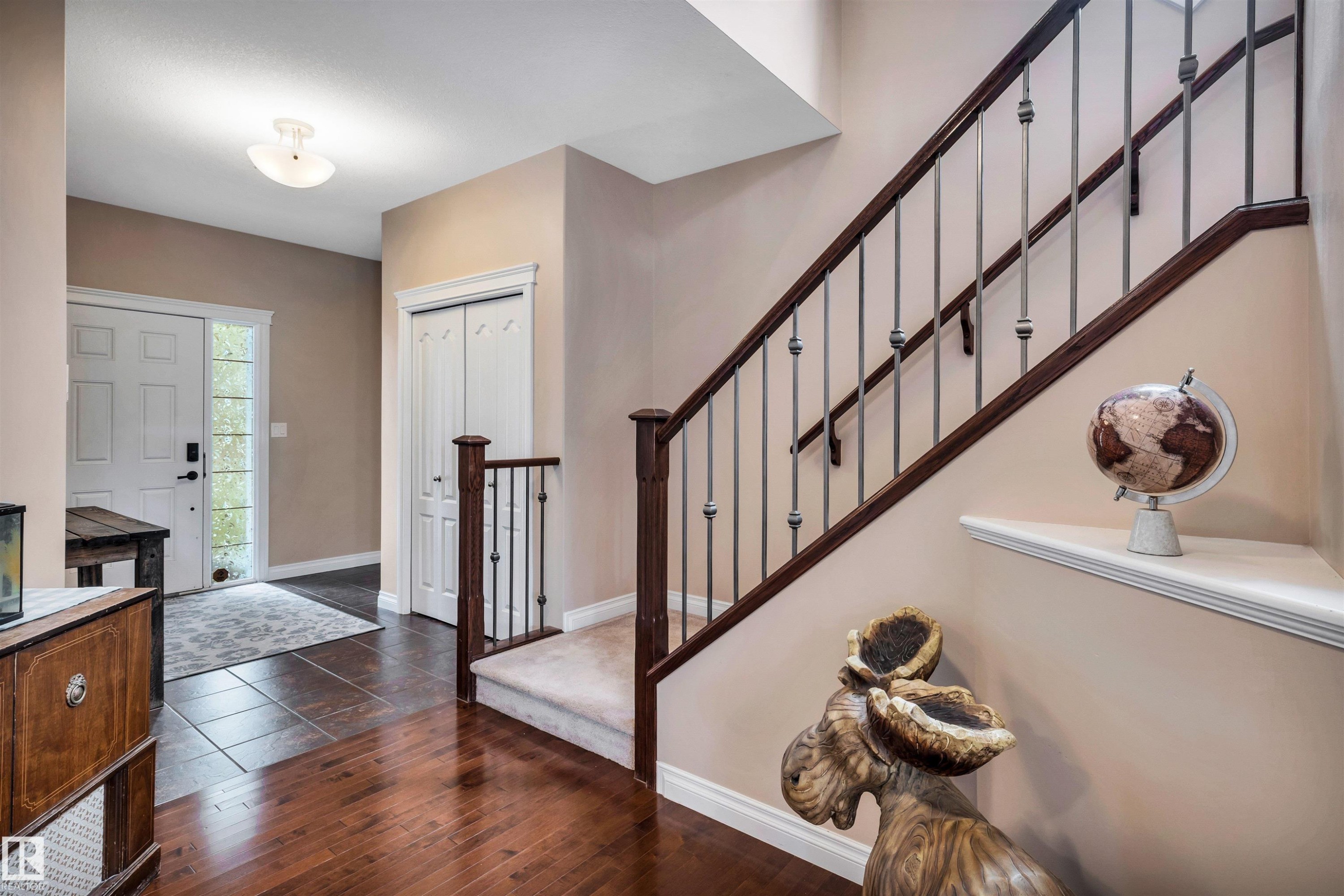 Staircase featuring dark wood handrails and decorative metal balusters - 18 Voleta Crest, Spruce Grove, AB