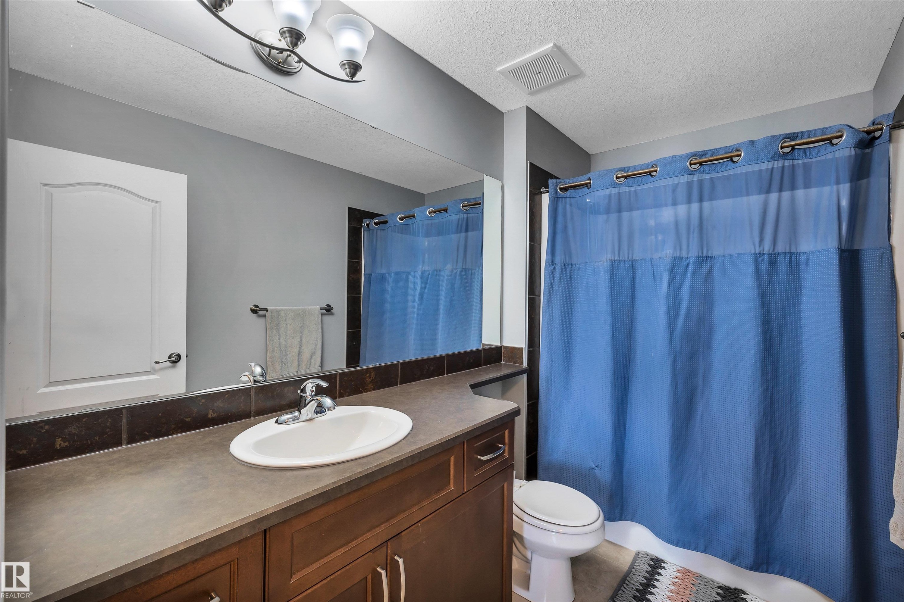 Bathroom featuring a vanity with an integrated sink, dark wood-finish cabinetry, and a full-width mirror - 18 Voleta Crest, Spruce Grove, AB