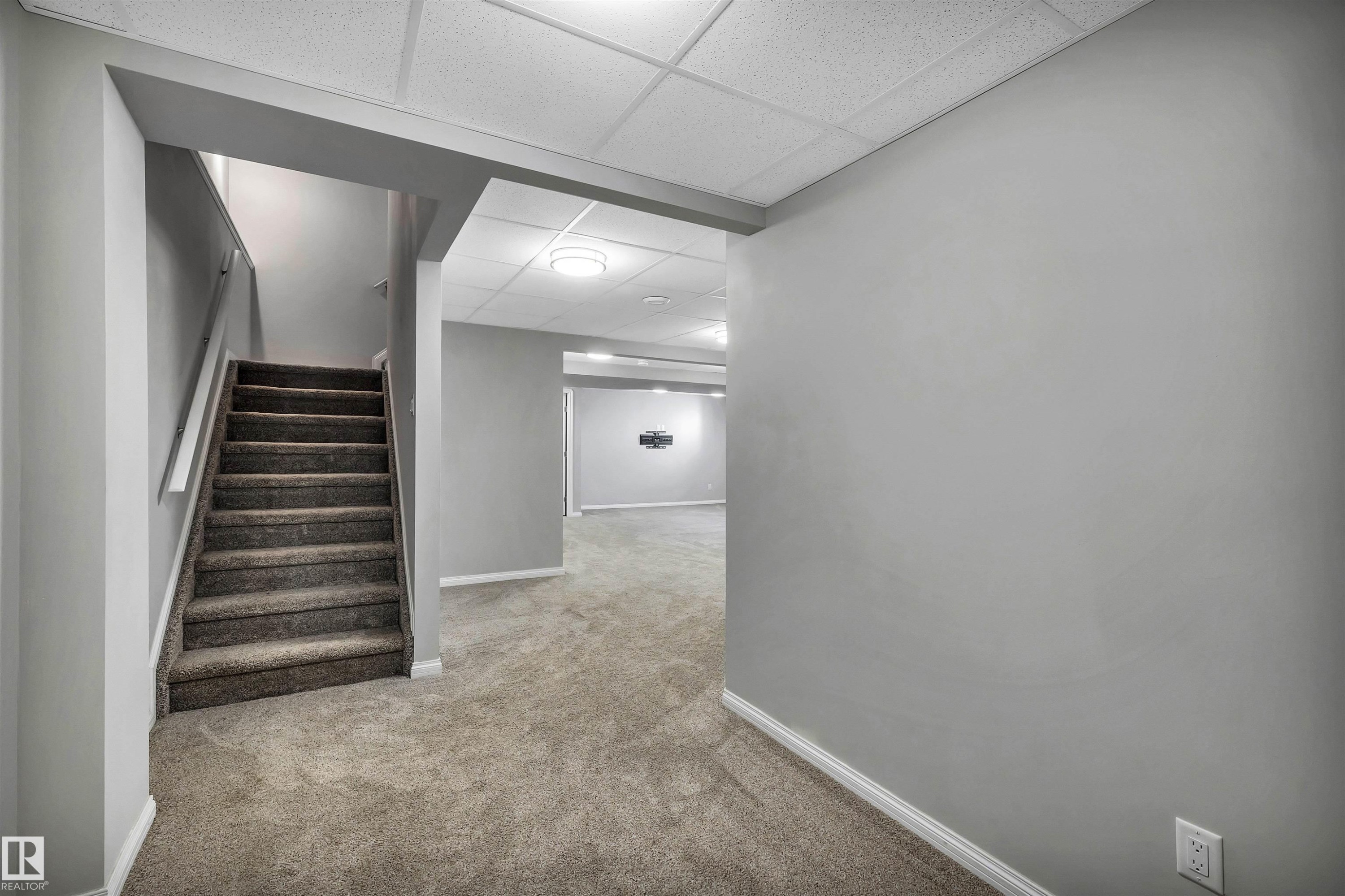 Carpeted staircase with white handrail leading to a finished lower level with recessed lighting, drop ceiling, and light gray wall paint - 18 Voleta Crest, Spruce Grove, AB