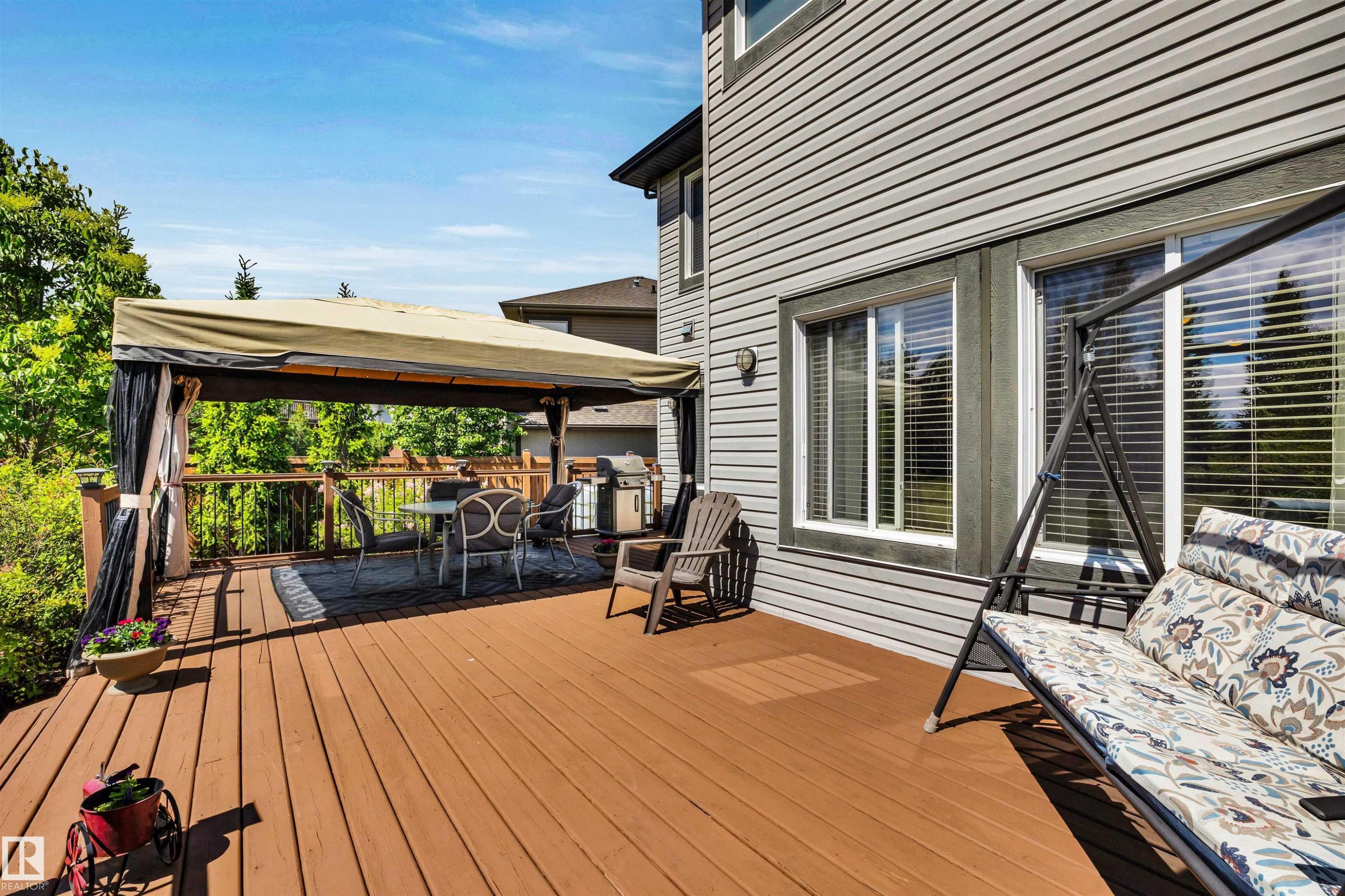 Spacious outdoor deck featuring brown wood-finish flooring, a covered patio area, and a horizontal siding exterior - 18 Voleta Crest, Spruce Grove, AB