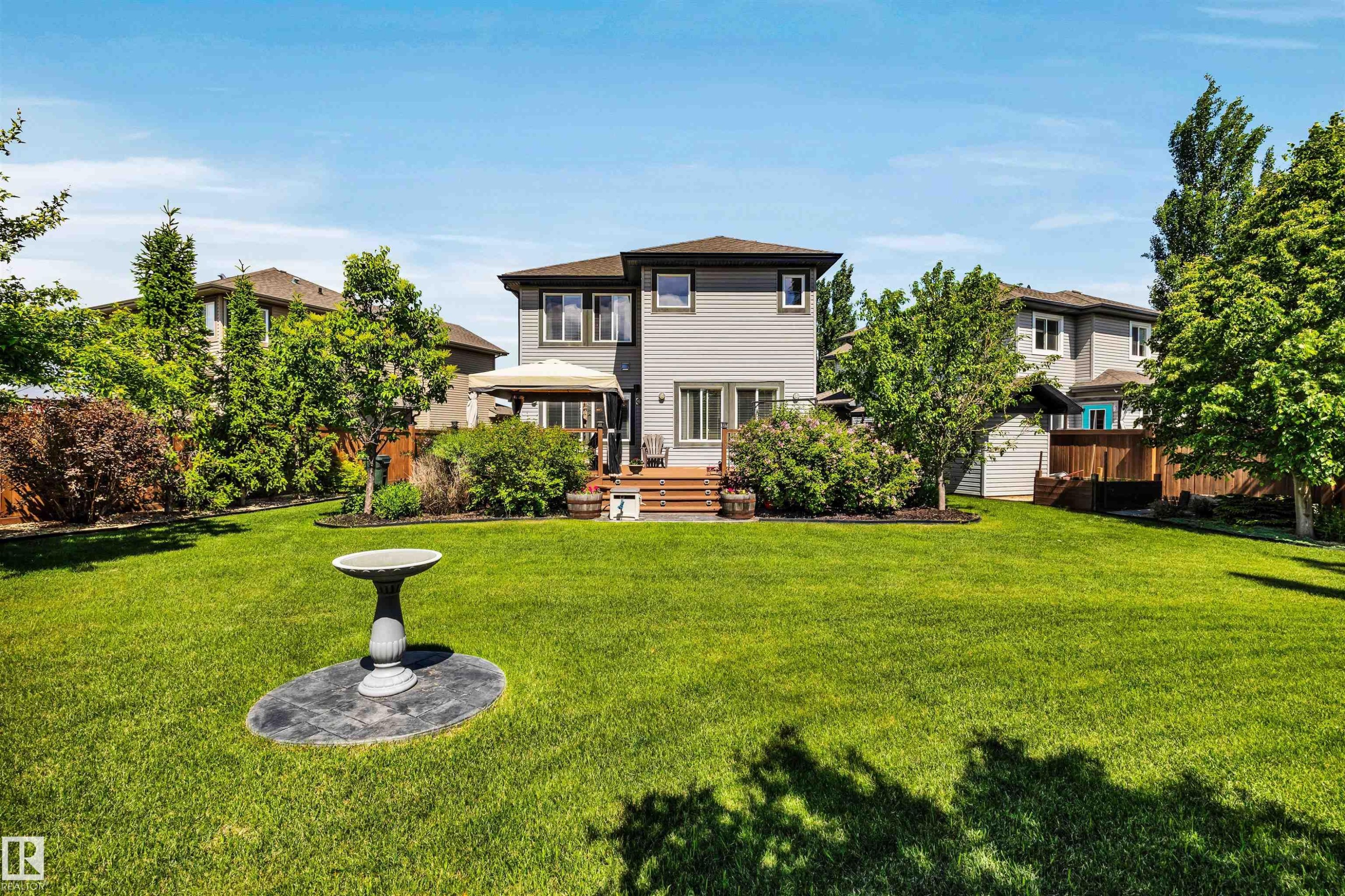 Expansive backyard featuring a lush lawn, mature trees, and privacy landscaping - 18 Voleta Crest, Spruce Grove, AB