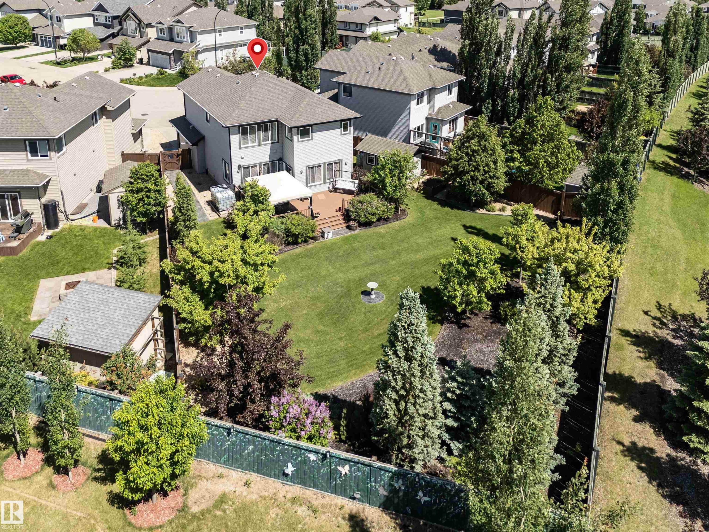 Spacious property featuring a large backyard, multi-level wood deck, established landscaping, mature trees, and a detached shed - 18 Voleta Crest, Spruce Grove, AB