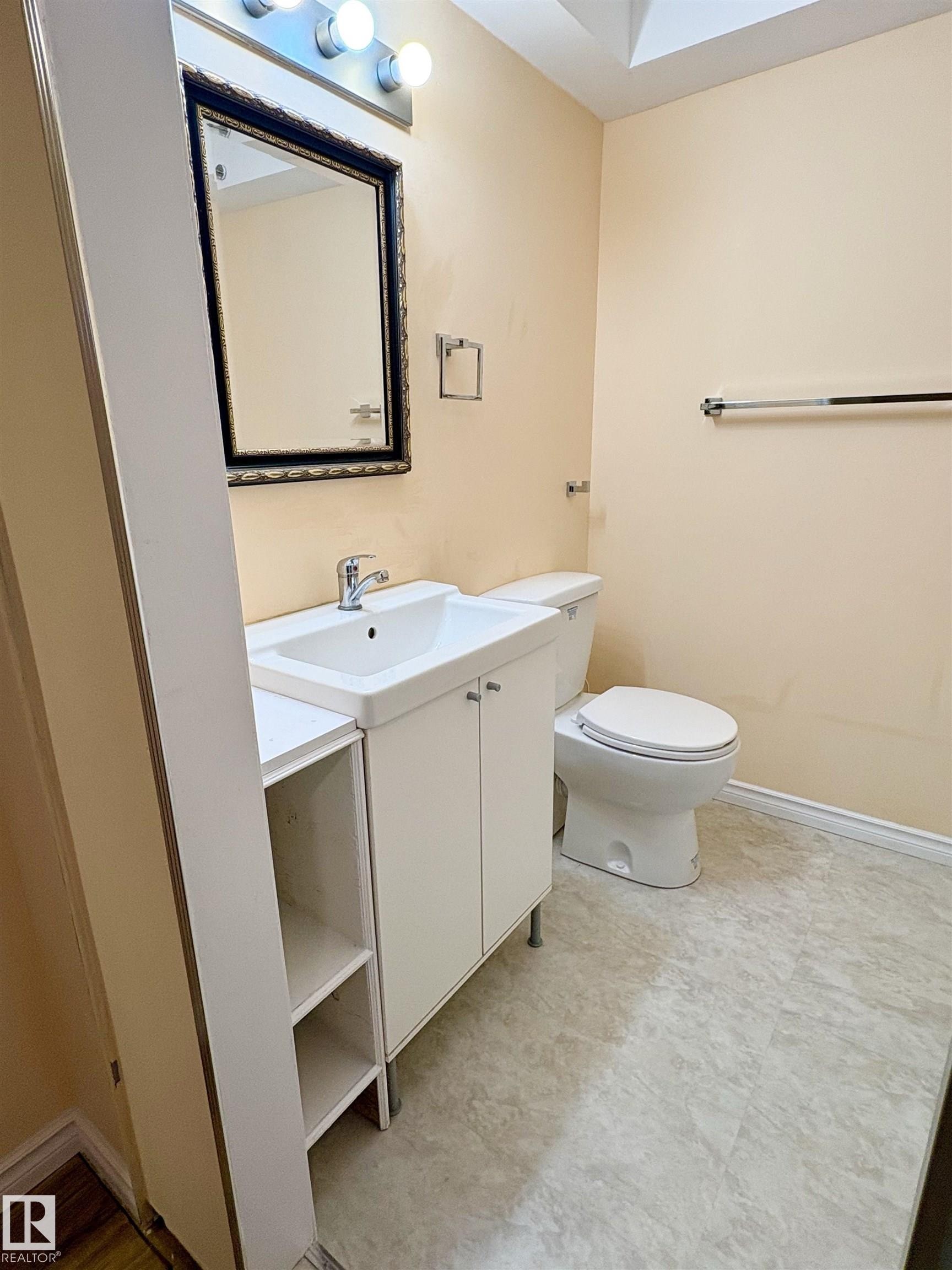 Bathroom featuring a white vanity with integrated sink, chrome faucet, and adjacent open shelving - 21354 87A Avenue, Edmonton, AB