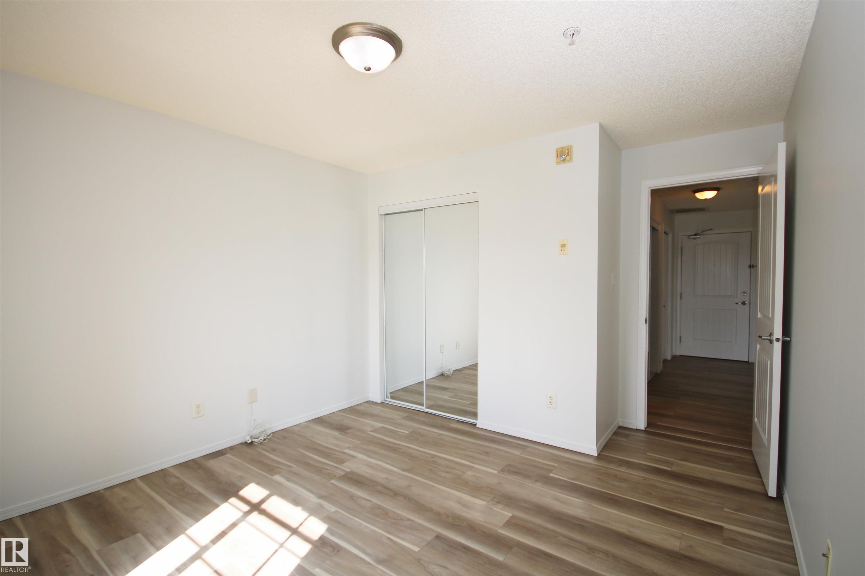 Room featuring wood-finish flooring, a flush-mount ceiling light, and white walls - 311 2098 Blackmud Creek Drive, Edmonton, AB