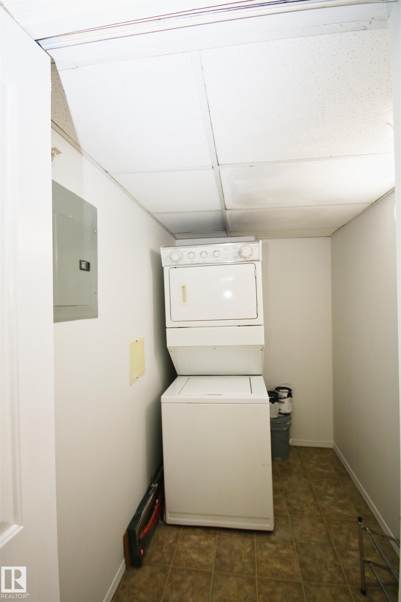 Laundry area featuring a stackable washer and dryer, tile flooring, and a drop ceiling - 311 2098 Blackmud Creek Drive, Edmonton, AB