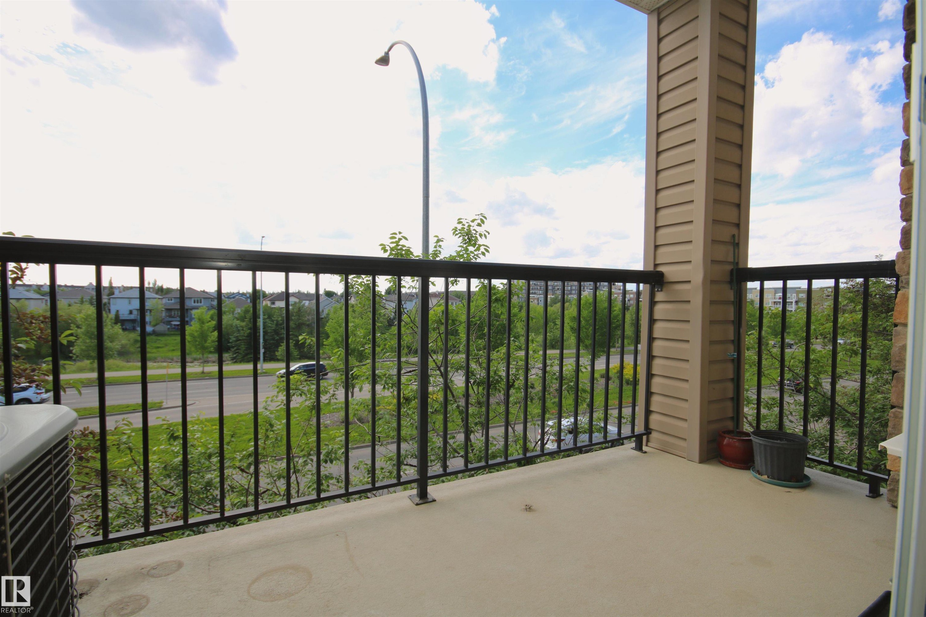 Private balcony featuring a concrete surface, black metal railings, and a beige siding column - 311 2098 Blackmud Creek Drive, Edmonton, AB