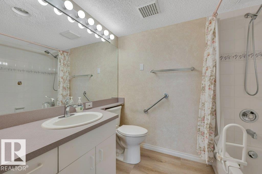 Bathroom featuring a vanity with an integrated sink, a full-width mirror, and a wall-mounted light bar - 316 2011 137 Avenue, Edmonton, AB - Indoor Photo Showing Bathroom