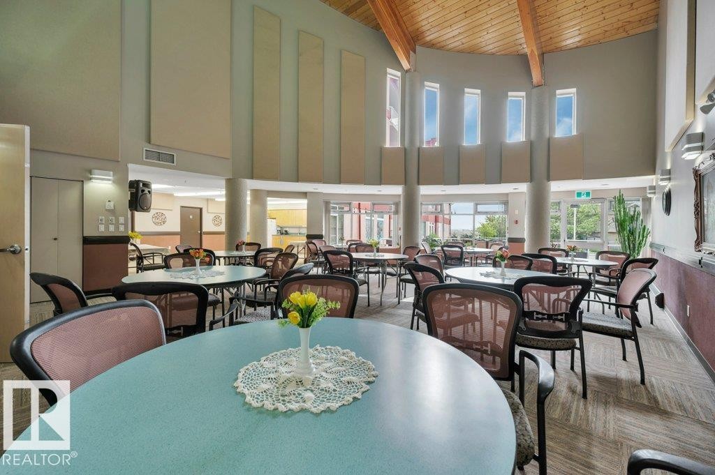 Spacious communal area featuring a high vaulted wood-beam ceiling and multiple round tables - 316 2011 137 Avenue, Edmonton, AB - Indoor Photo Showing Dining Room
