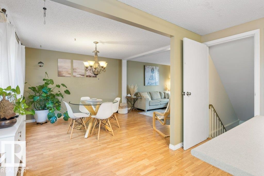 Dining area featuring wood-finish flooring, a decorative chandelier, and a wide entryway to another room - 171 Ridgewood, St. Albert, AB