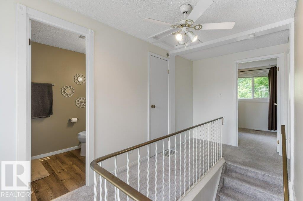 Hallway featuring textured carpeting and a white painted railing with a brass-finish top - 171 Ridgewood, St. Albert, AB