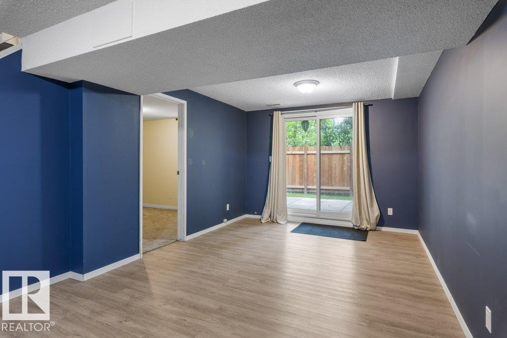 Room featuring wood-finish flooring, blue painted walls, and white trim - 171 Ridgewood, St. Albert, AB