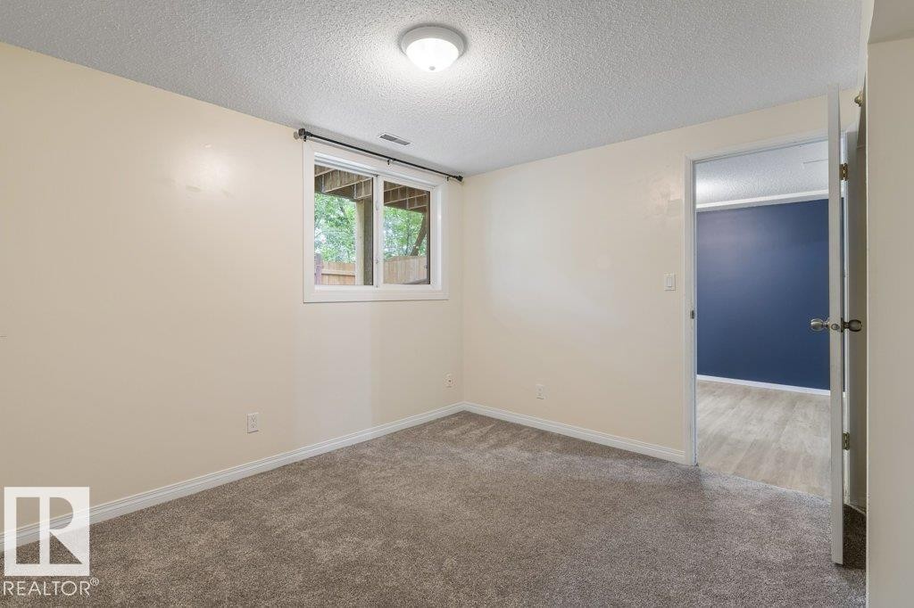Carpeted room with a single window, overhead lighting, and white baseboards - 171 Ridgewood, St. Albert, AB