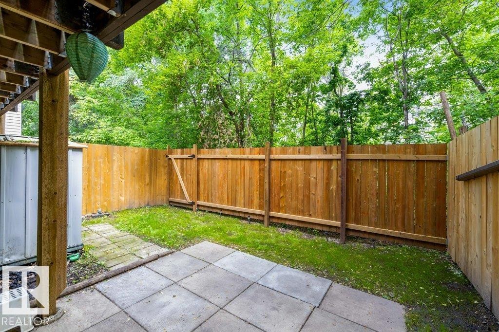 Patio area with square pavers, bordered by a wooden privacy fence - 171 Ridgewood, St. Albert, AB