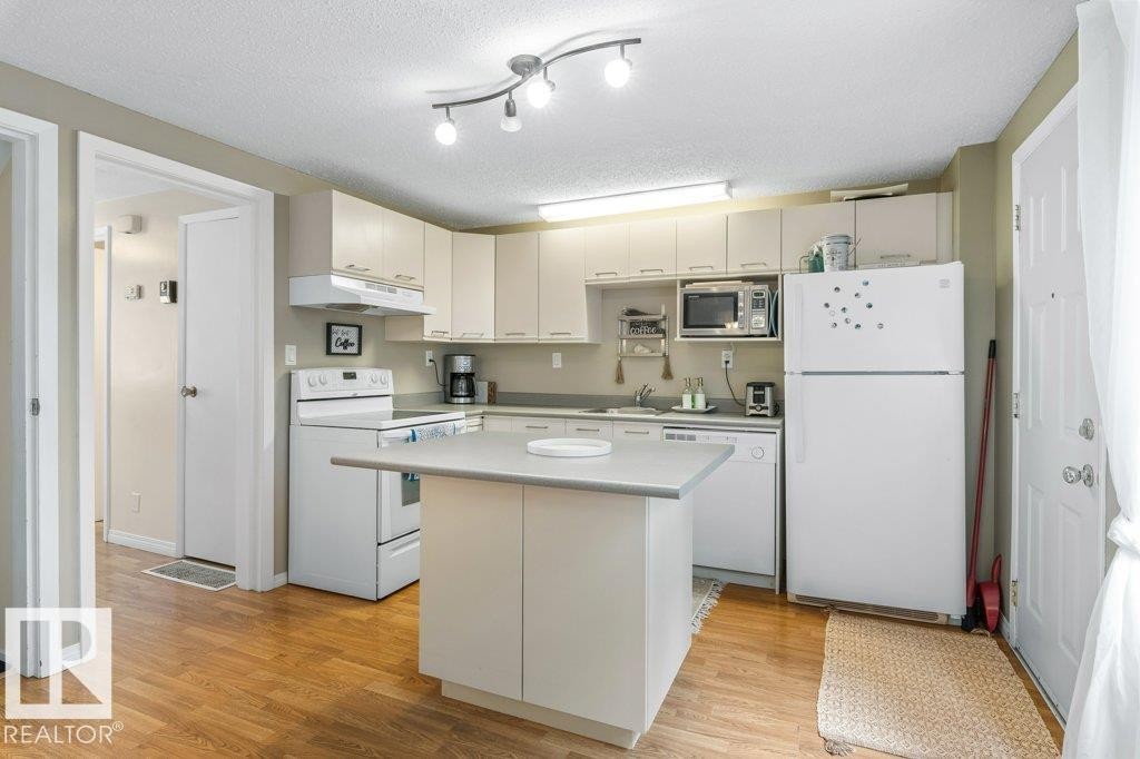 Kitchen featuring wood-finish flooring, an island with countertop, and white cabinetry - 171 Ridgewood, St. Albert, AB