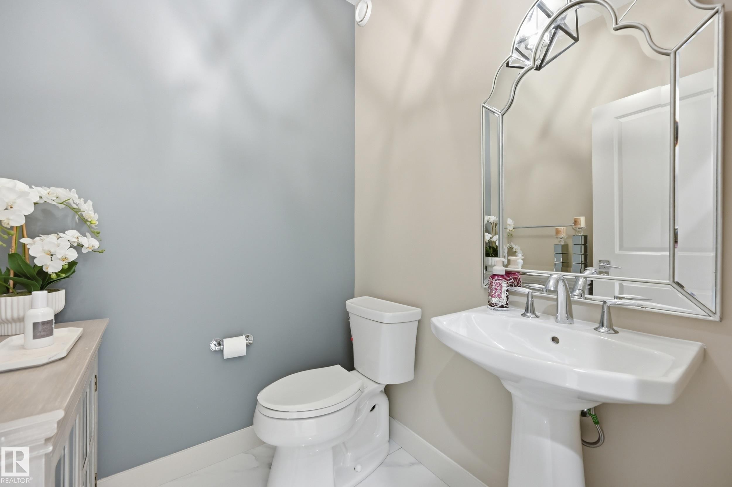 Pedestal sink with chrome fixtures and an ornate framed mirror - 76 Jacobs Close, St. Albert, AB