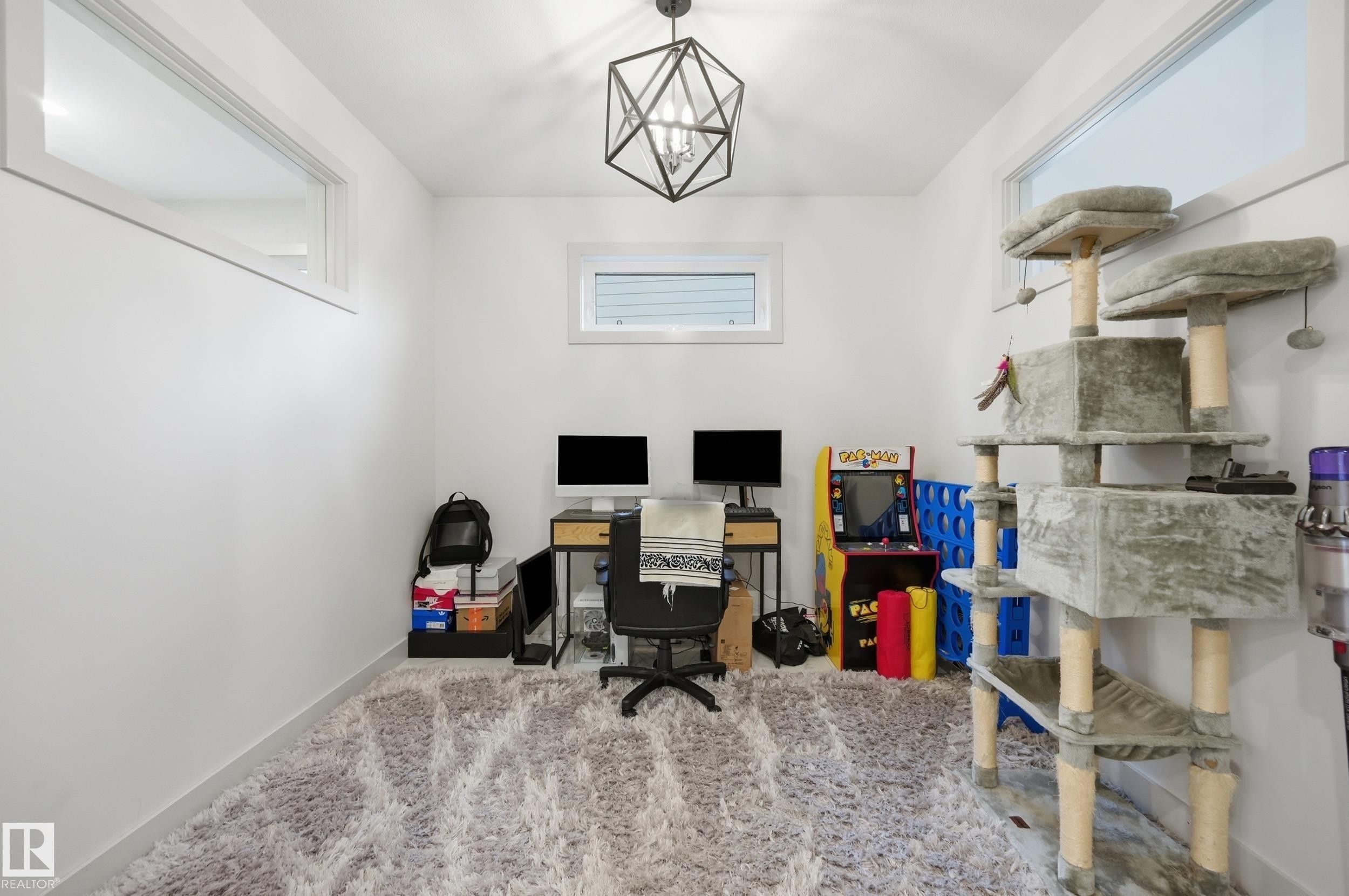 Bright interior room featuring a geometric pendant light fixture, high windows, and plush carpeting - 76 Jacobs Close, St. Albert, AB
