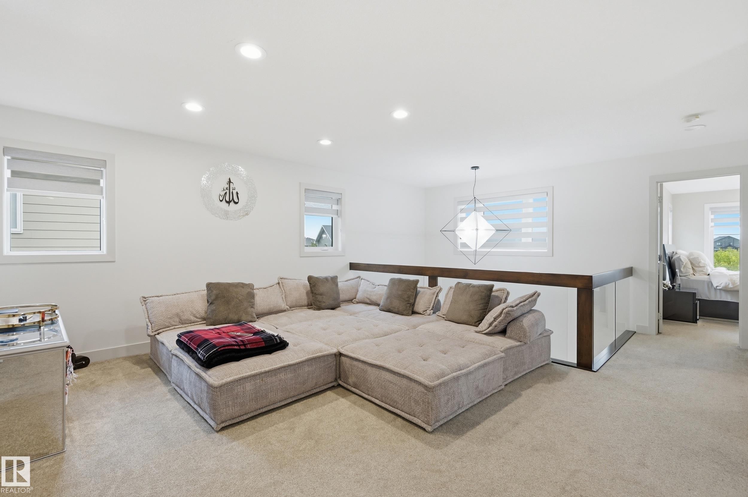 Open concept room featuring recessed lighting, multiple windows with blinds, a modern geometric pendant light, and light-toned carpeting - 76 Jacobs Close, St. Albert, AB