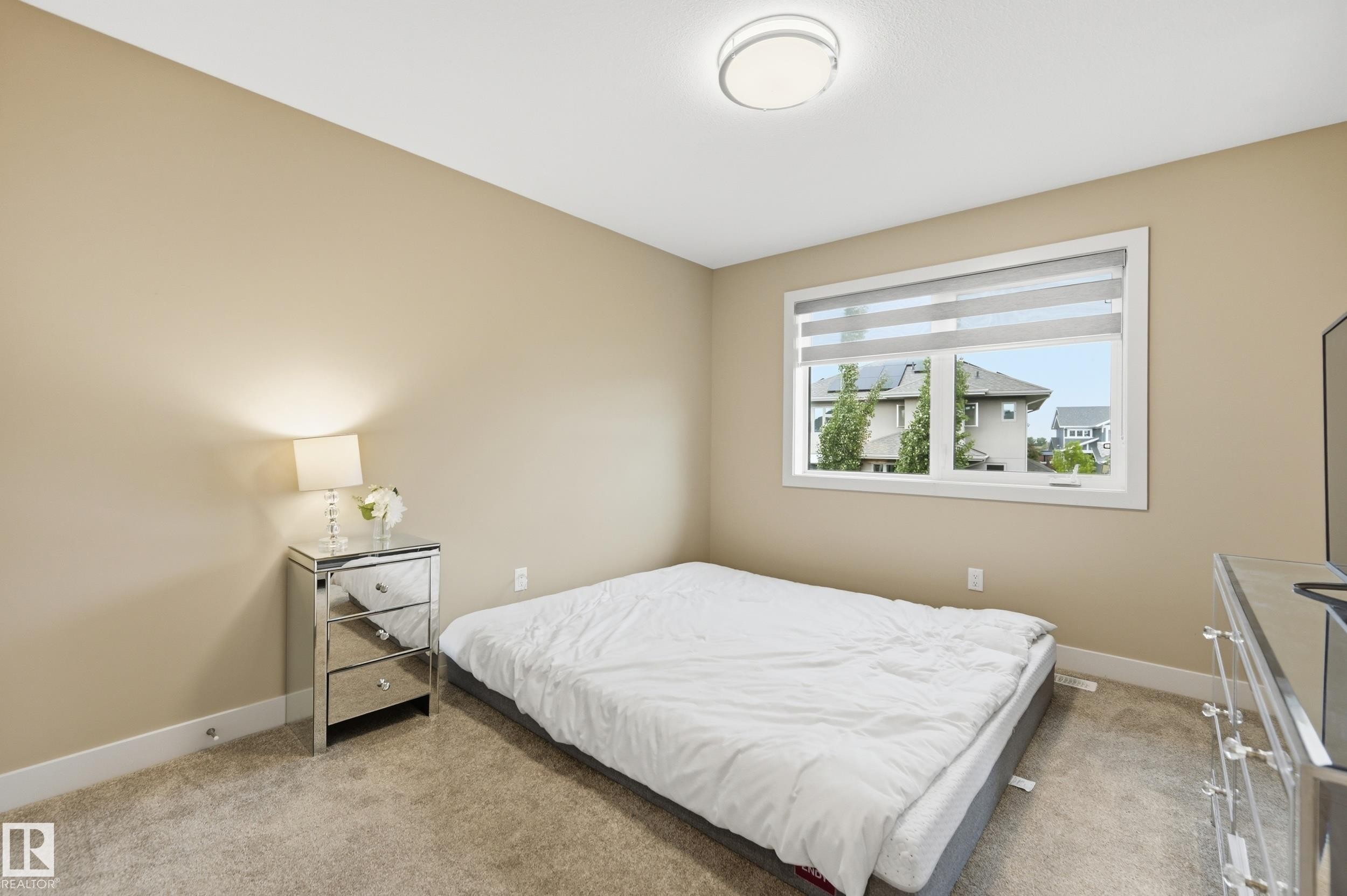 Carpeted bedroom with a large window featuring horizontal blinds - 76 Jacobs Close, St. Albert, AB