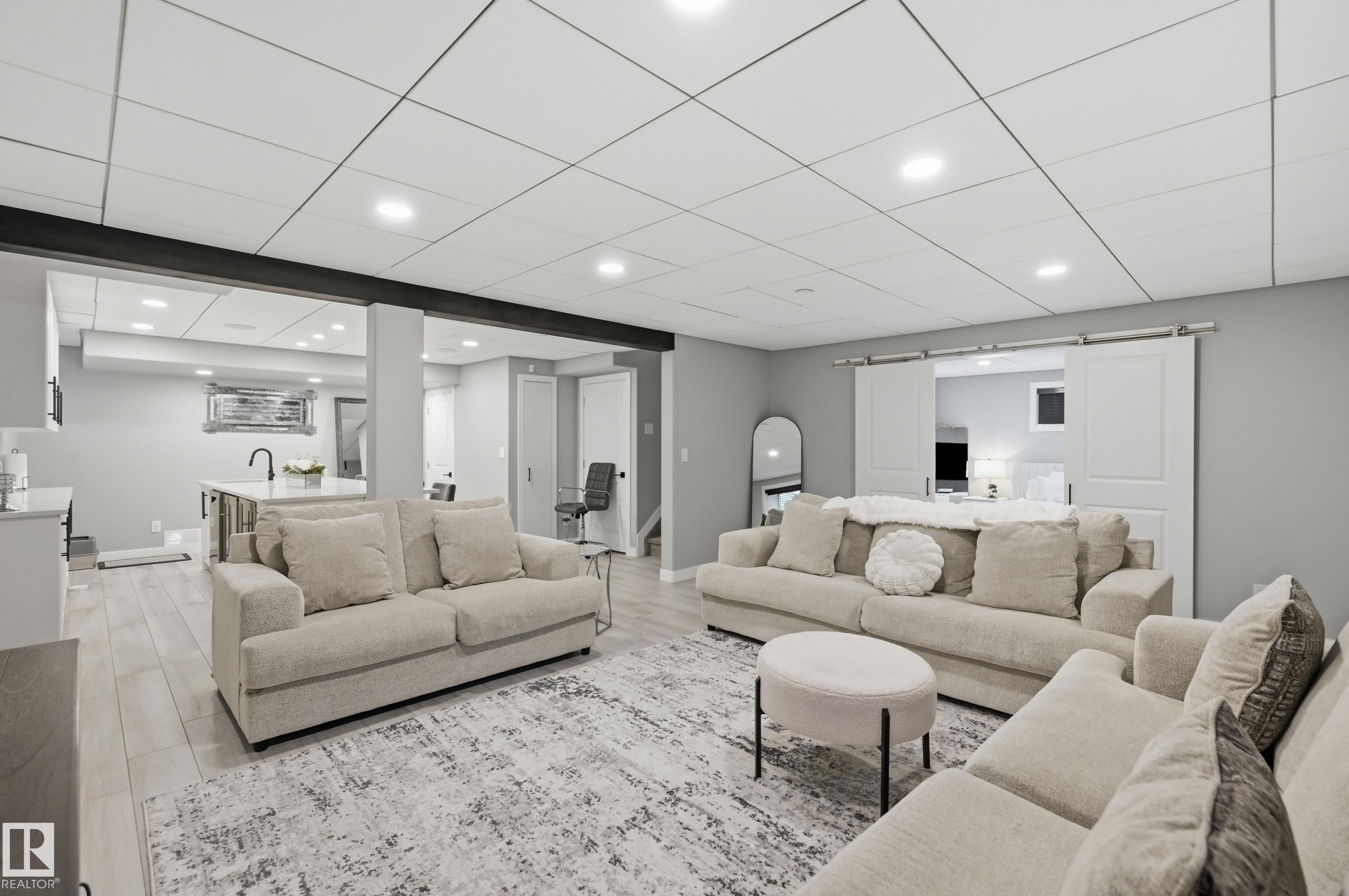 Spacious lower-level living area featuring light wood-finish flooring, recessed lighting, and a drop ceiling - 76 Jacobs Close, St. Albert, AB