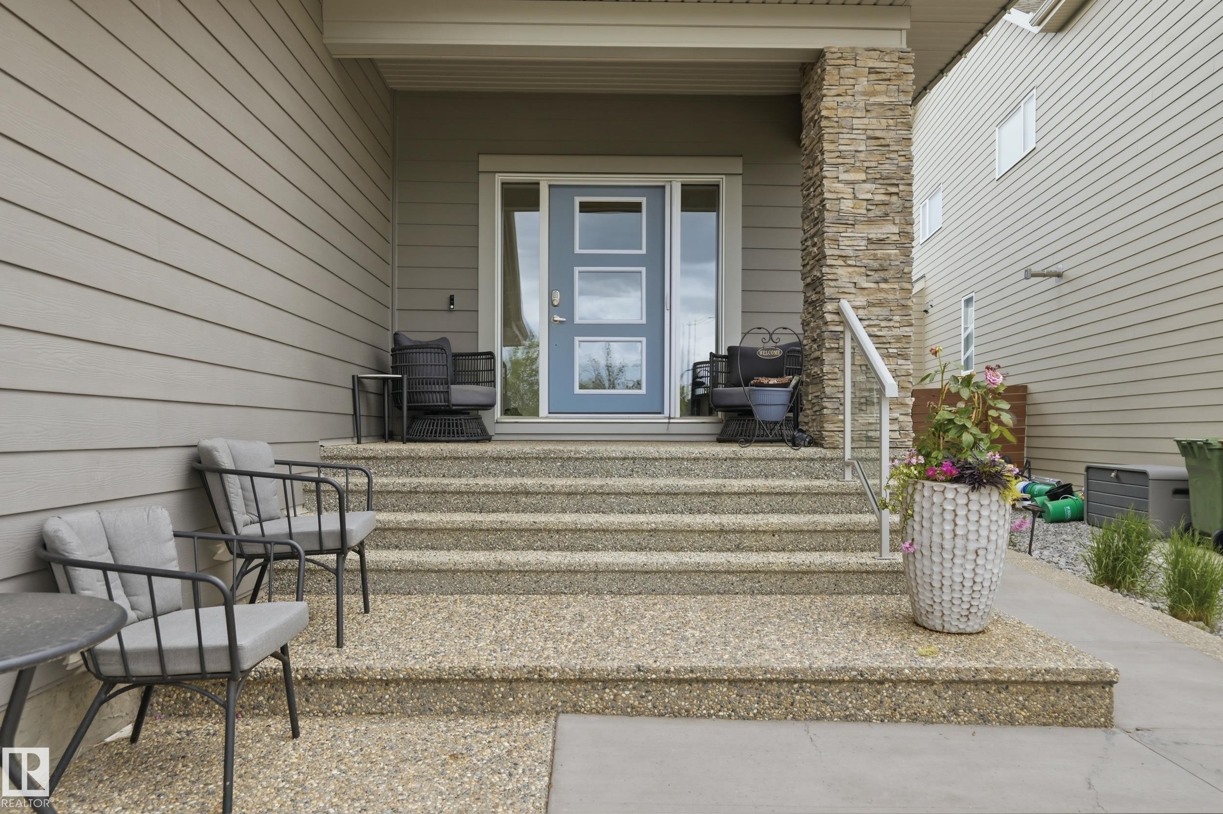 Inviting front entry featuring exposed aggregate steps and a light blue door with frosted glass panels - 76 Jacobs Close, St. Albert, AB