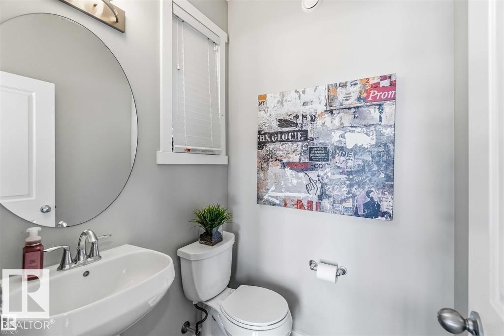 Pedestal sink with chrome fixtures and a circular mirror - 1908 25 Street Nw, Edmonton, AB