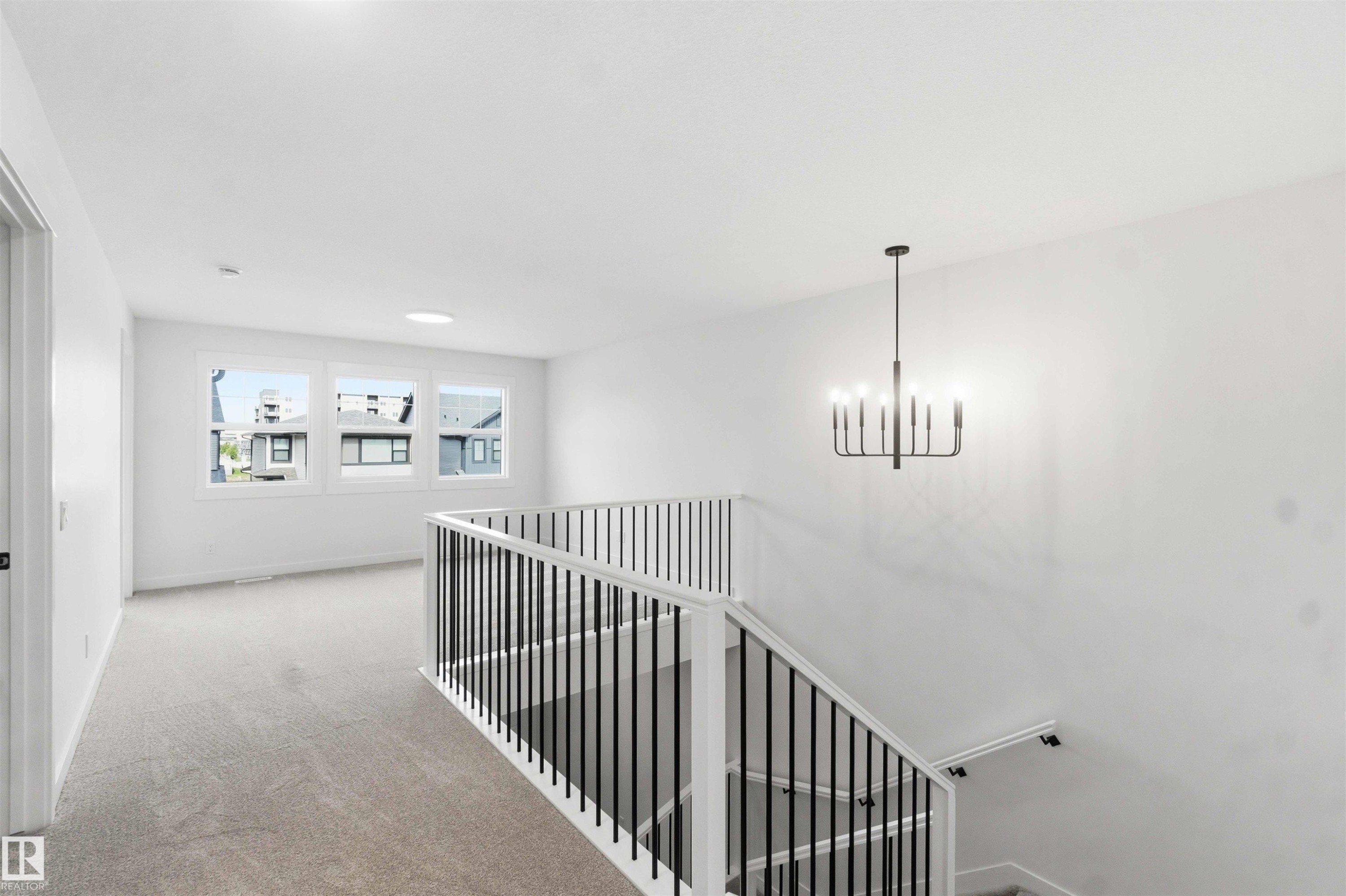 Upper-level landing featuring a contemporary chandelier, white walls, and light-toned carpeting - 1085 Cristall Crescent Sw, Edmonton, AB - Indoor Photo Showing Other Room