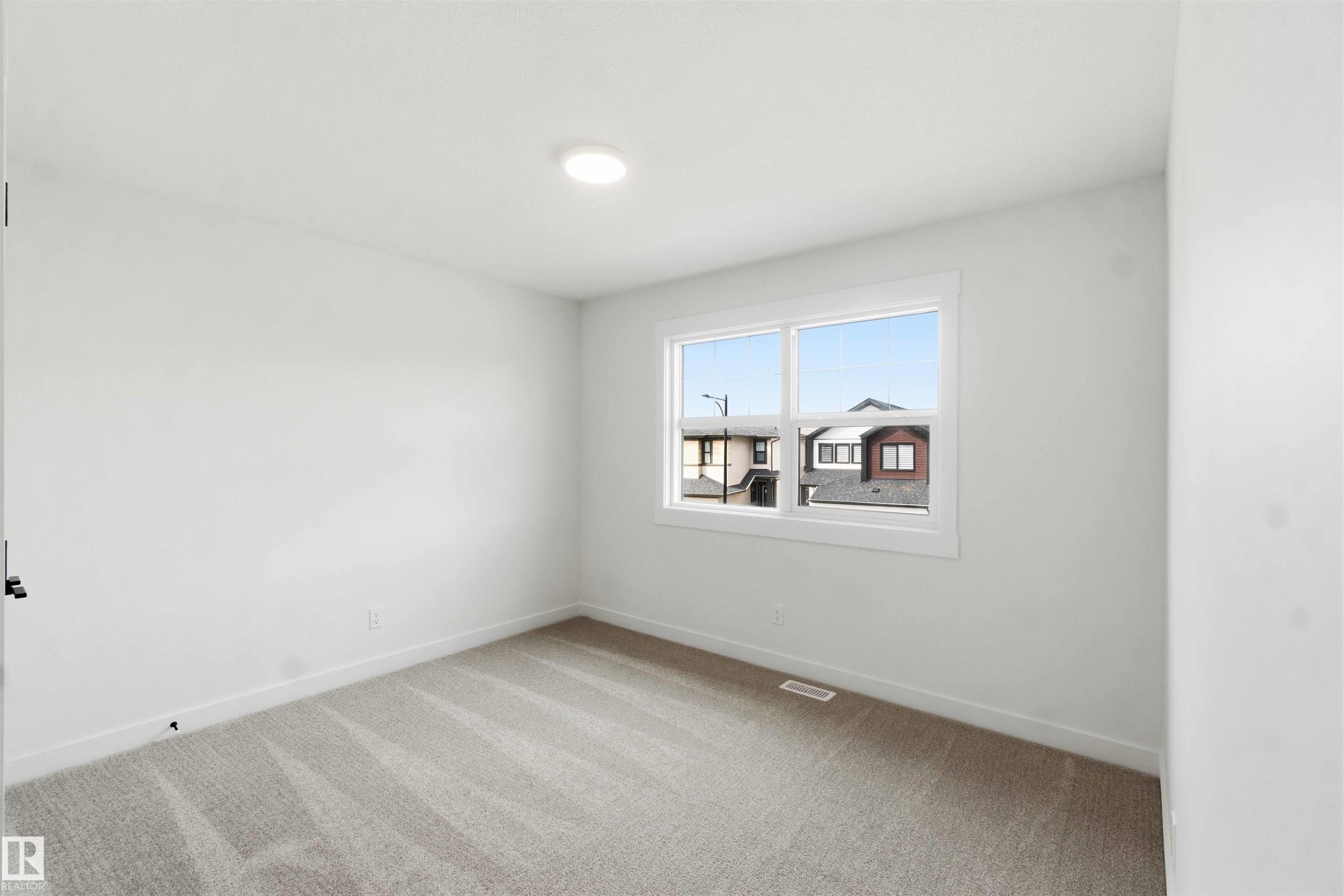 Bedroom featuring neutral-toned carpet, white walls, and a large window with white trim - 1085 Cristall Crescent Sw, Edmonton, AB - Indoor Photo Showing Other Room