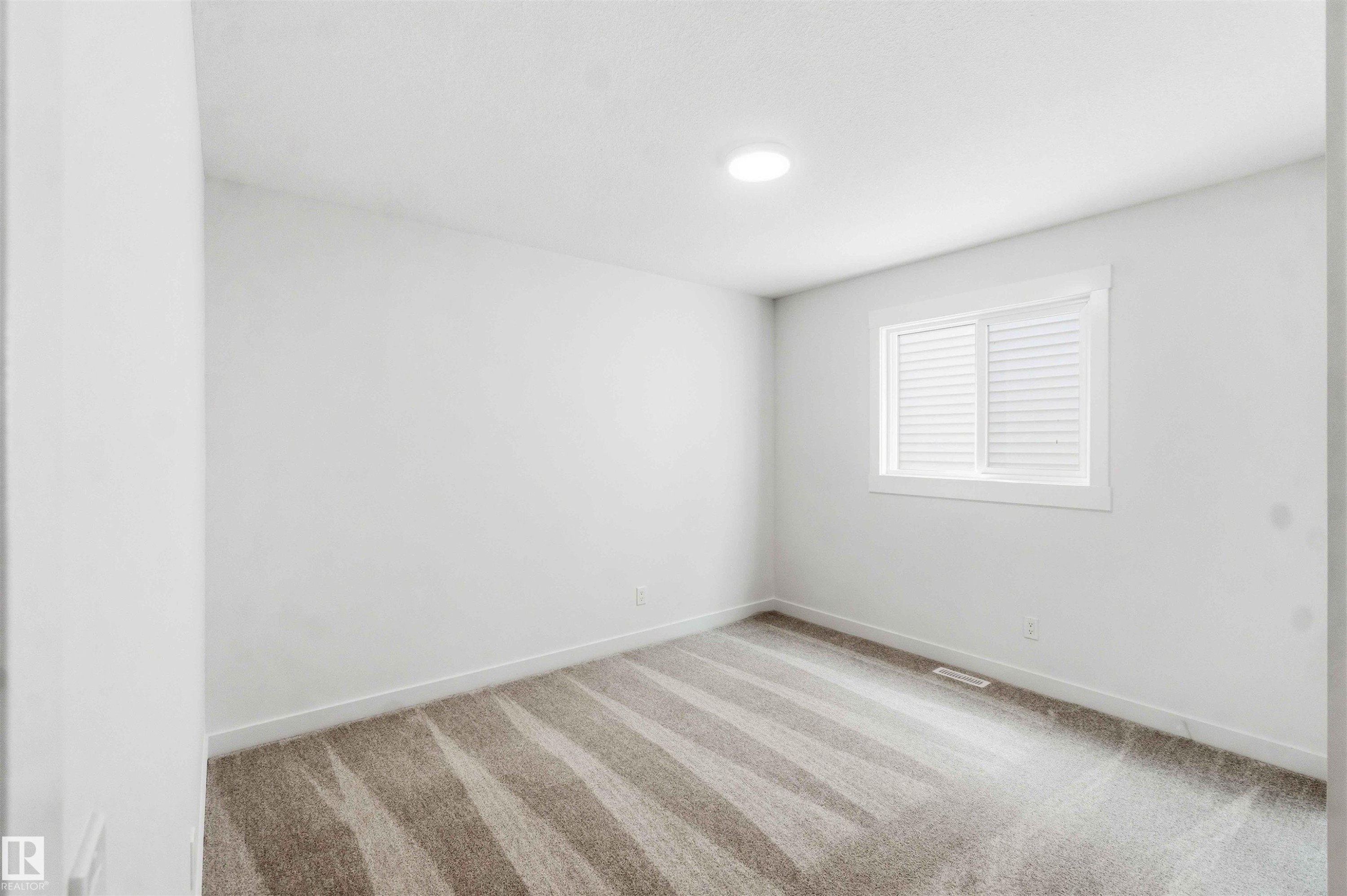Room featuring neutral-toned patterned carpet, white walls, and a window with white louvered blinds - 1085 Cristall Crescent Sw, Edmonton, AB - Indoor Photo Showing Other Room