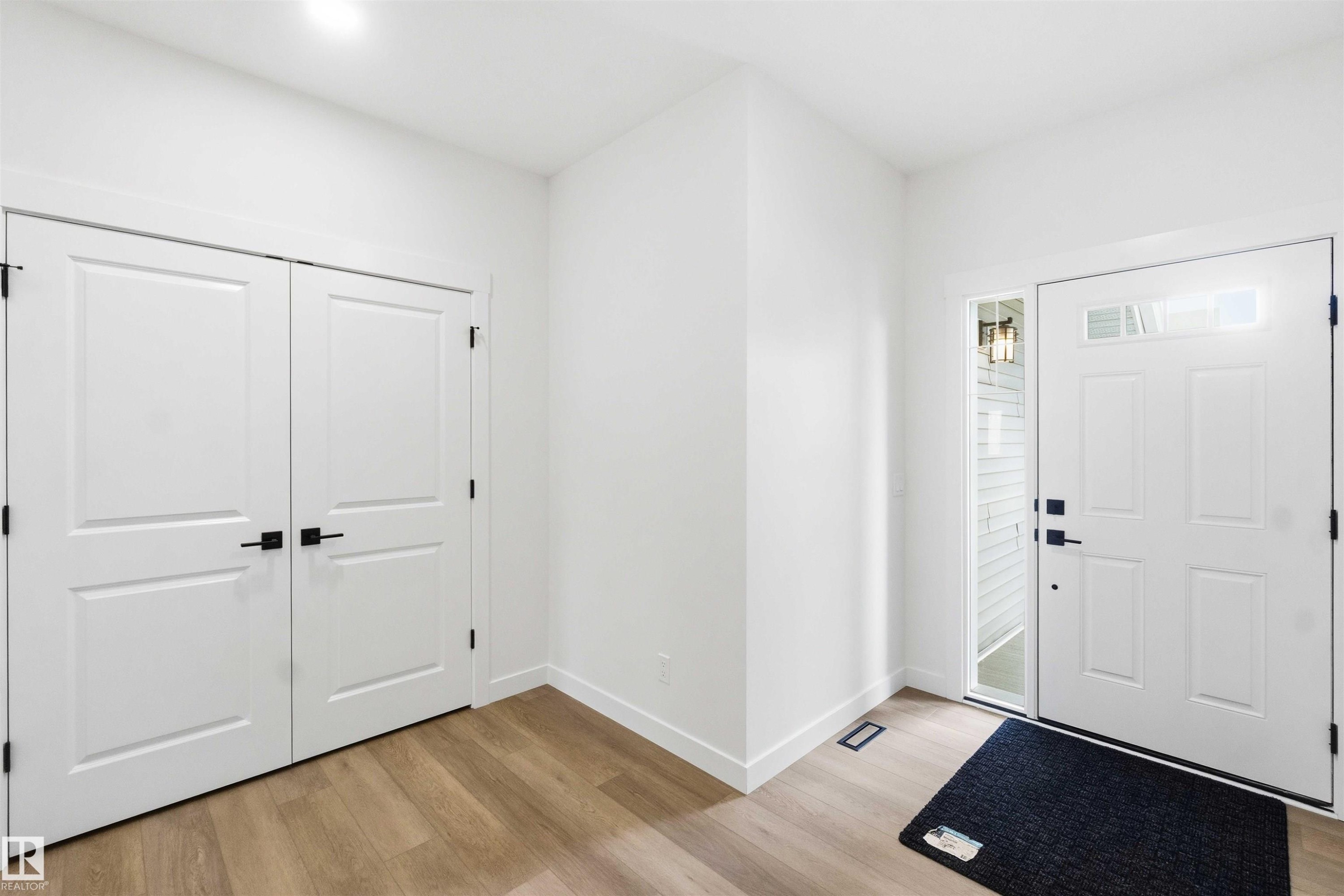 Entryway featuring wood-finish flooring and a white paneled door with transom and sidelite windows - 1085 Cristall Crescent Sw, Edmonton, AB - Indoor Photo Showing Other Room