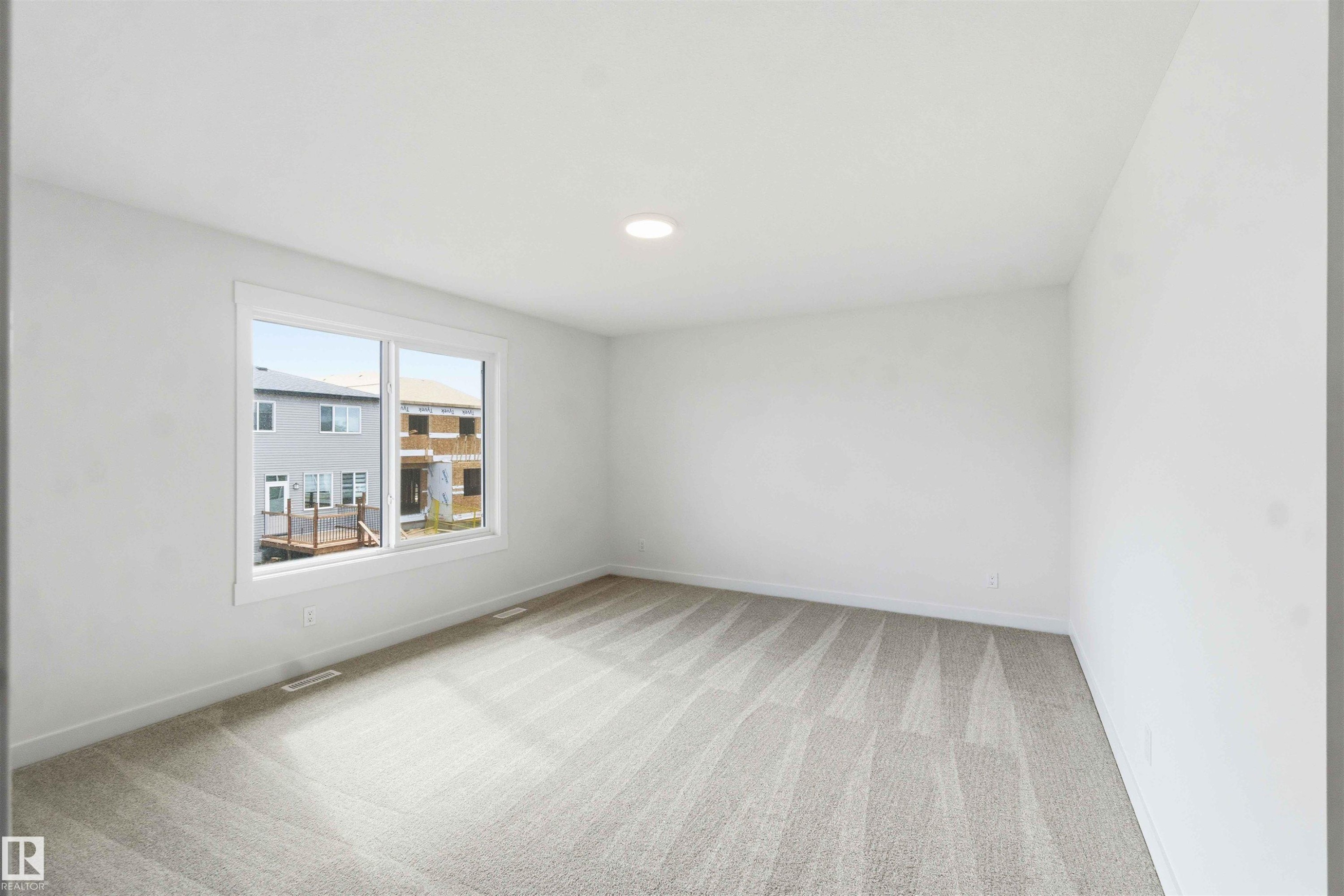 Bright interior space featuring a large window, recessed lighting, and neutral-toned wall-to-wall carpeting - 1085 Cristall Crescent Sw, Edmonton, AB - Indoor Photo Showing Other Room