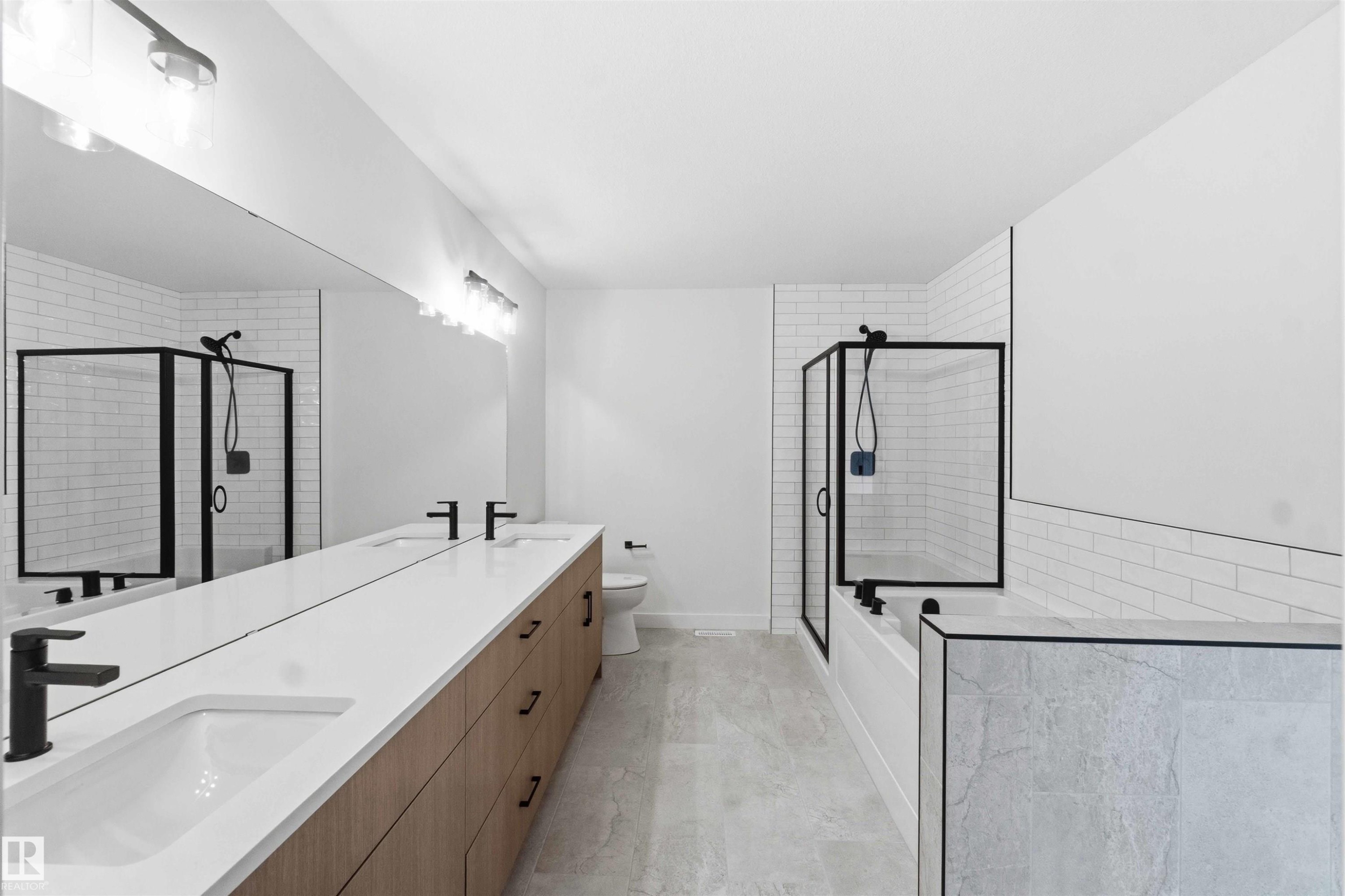 Contemporary bathroom featuring a long wood-finish vanity with dual integrated sinks, matte black faucets, and a full-width mirror - 1085 Cristall Crescent Sw, Edmonton, AB - Indoor Photo Showing Bathroom