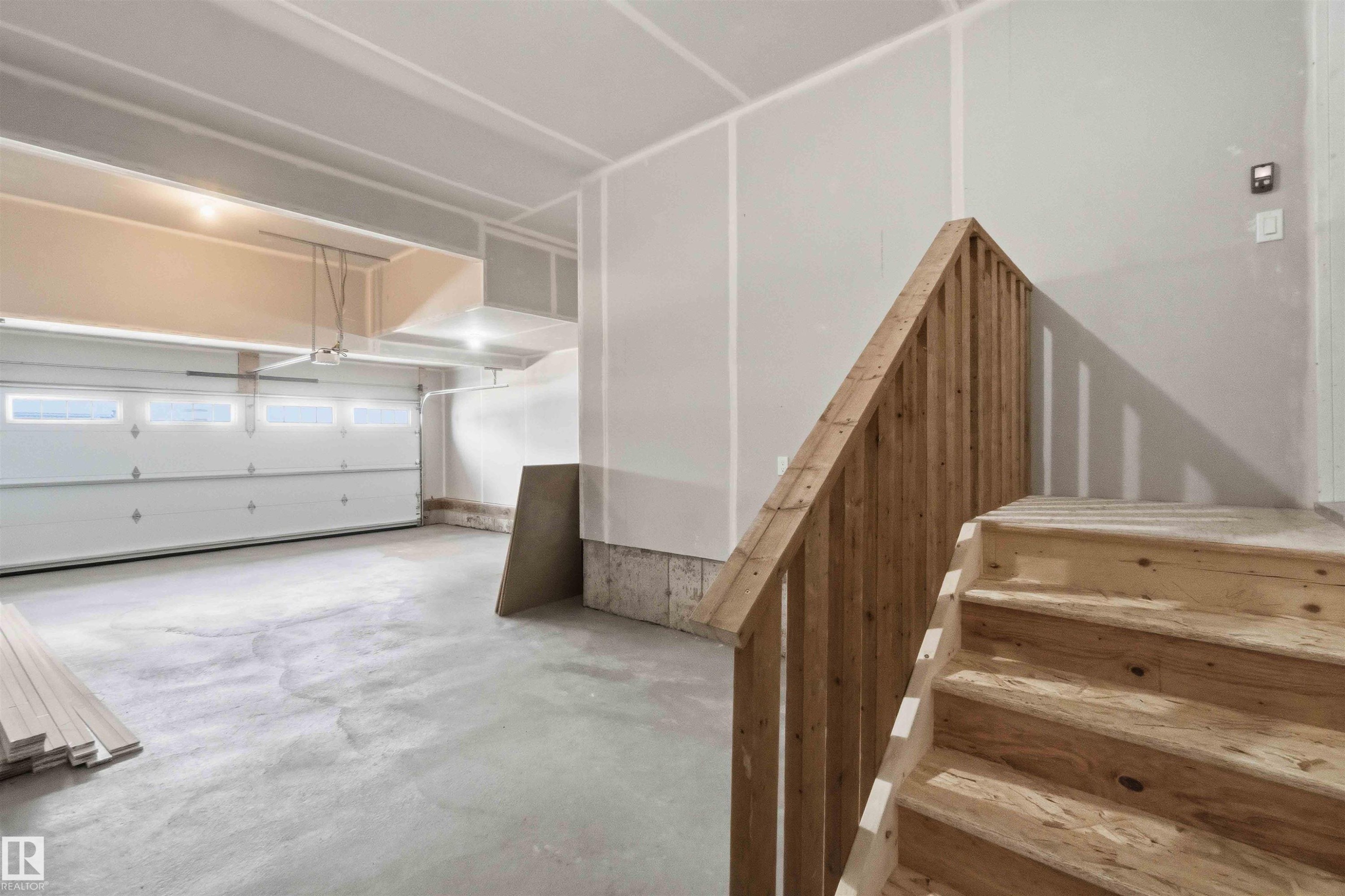 Spacious garage with a concrete floor, overhead lighting, and an automatic overhead door with transom window inserts - 1085 Cristall Crescent Sw, Edmonton, AB - Indoor Photo Showing Garage