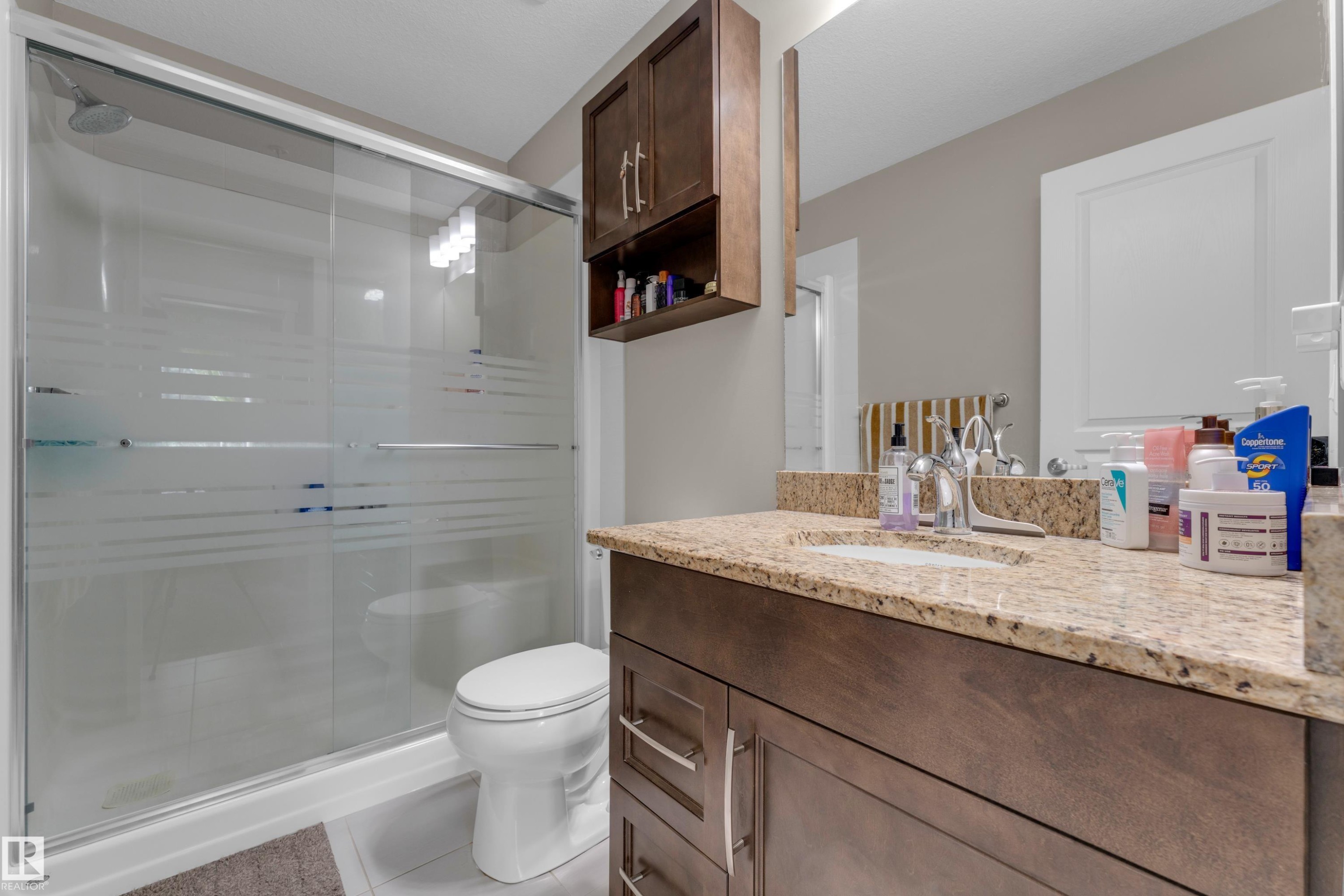Bathroom with a dark wood-finish vanity, light-toned countertop, and undermount sink - 115 812 Welsh Drive Sw, Edmonton, AB
