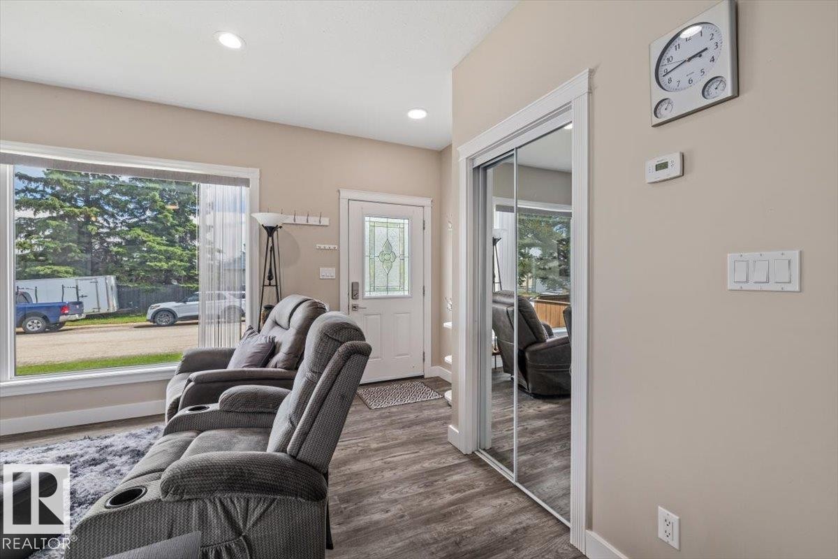 Living room featuring wood-finish flooring, recessed lighting, and a large front-facing window - 4708 47A Avenue, Onoway, AB