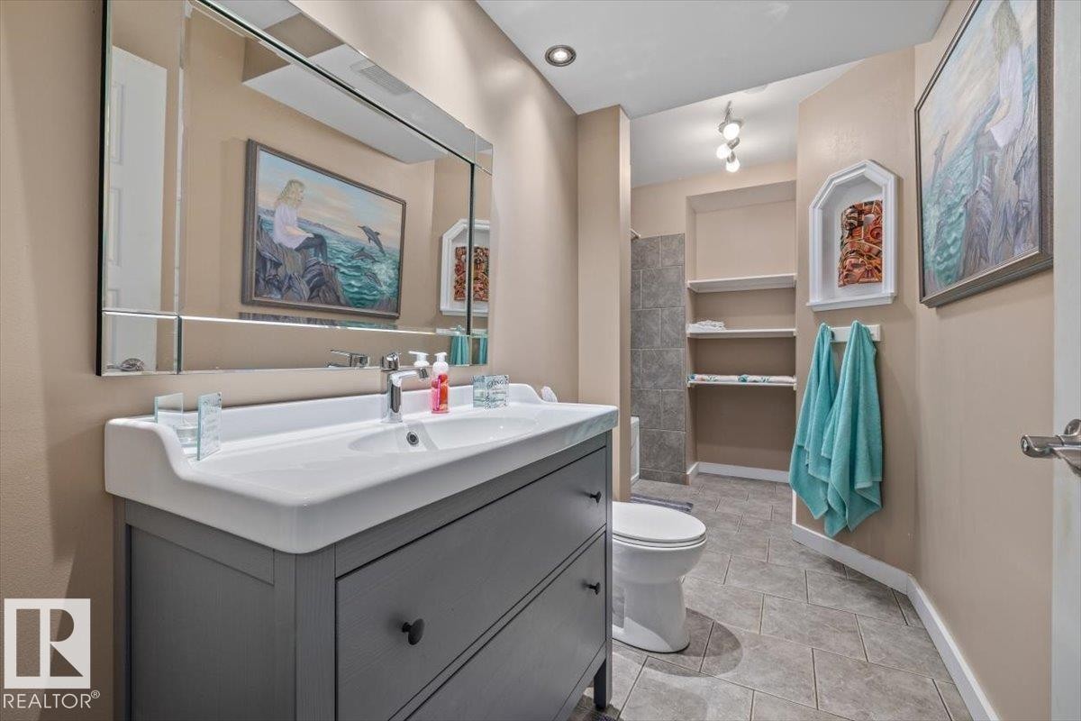 Bathroom featuring a contemporary vanity with an integrated sink, a large wall-mounted mirror, recessed lighting, and tiled flooring - 4708 47A Avenue, Onoway, AB
