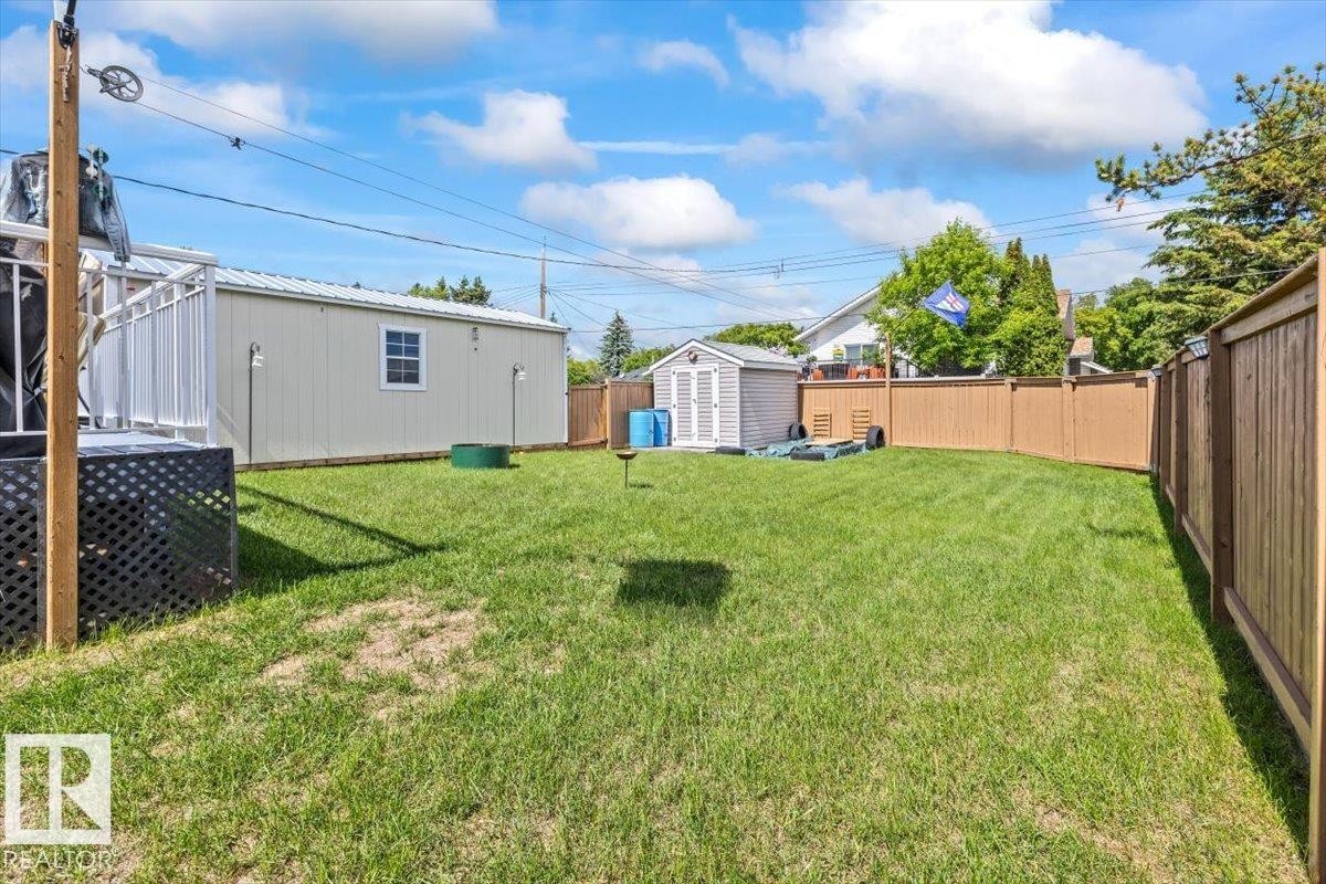 Expansive green lawn surrounded by a privacy fence, featuring a large shed with a window, and a smaller storage shed - 4708 47A Avenue, Onoway, AB