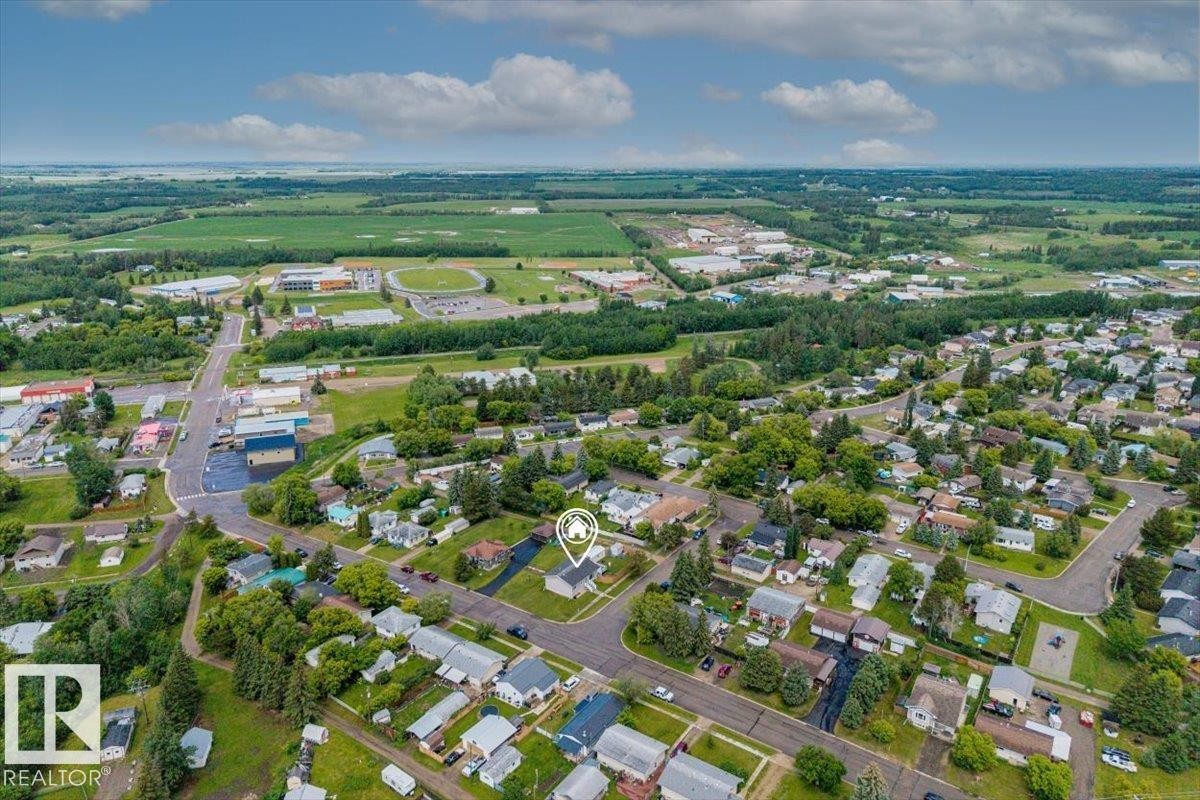 Aerial perspective showcasing a residential neighborhood with surrounding green spaces and agricultural fields - 4708 47A Avenue, Onoway, AB