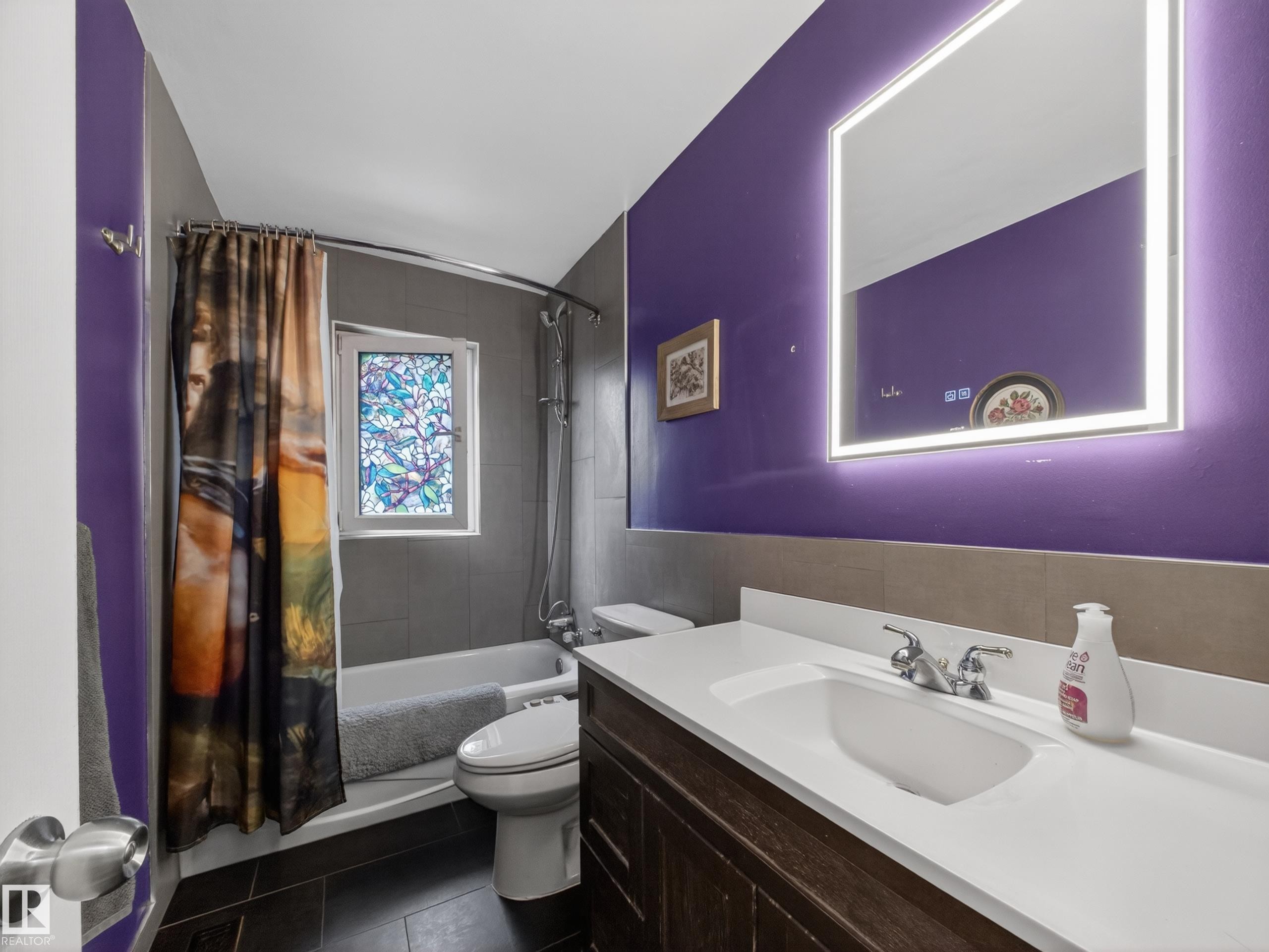 Bathroom featuring a dark wood-finish vanity with an integrated white sink and a lighted mirror - 10809 150 Street, Edmonton, AB