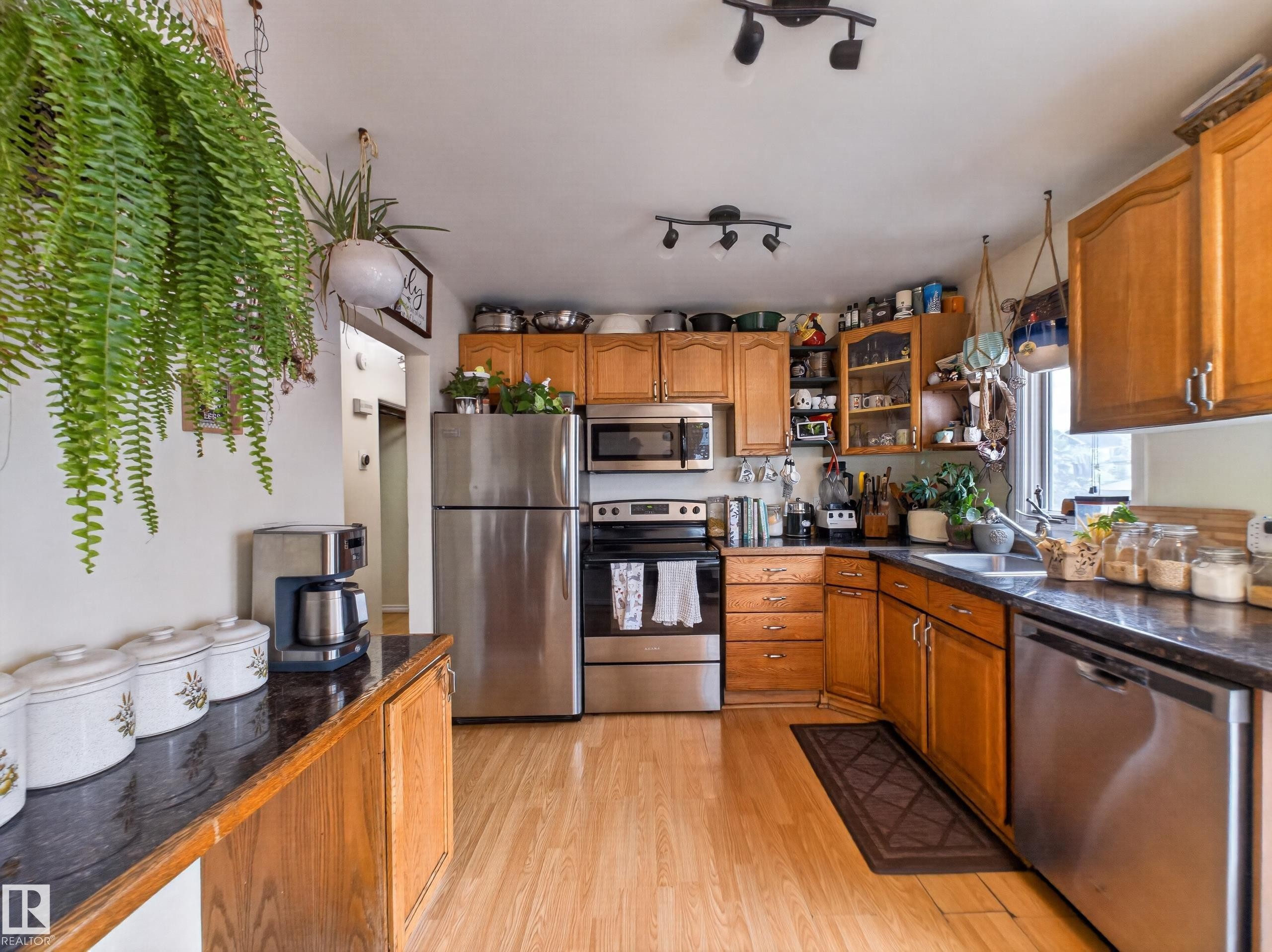Kitchen featuring wood-finish flooring, dark countertops, and light-toned cabinetry - 10809 150 Street, Edmonton, AB