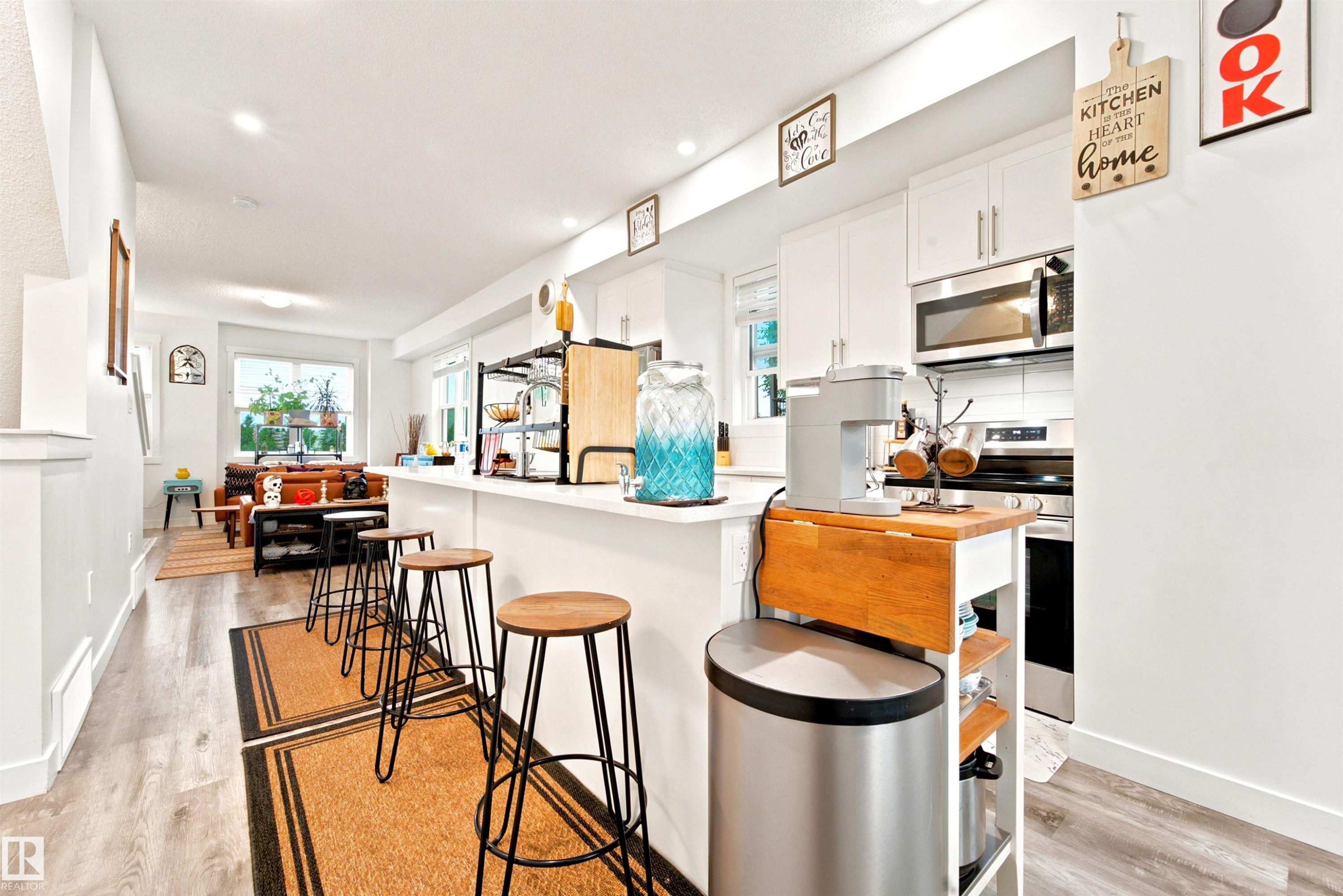 Open-concept kitchen with white cabinetry and stainless steel appliances - 64 655 Watt Boulevard, Edmonton, AB