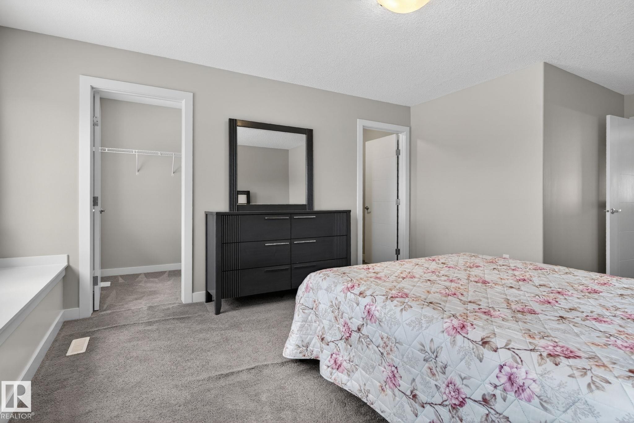 Spacious room featuring neutral paint, gray carpet, a built-in window bench, and a closet with shelving - 7341 Armour Crescent, Edmonton, AB - Indoor Photo Showing Bedroom