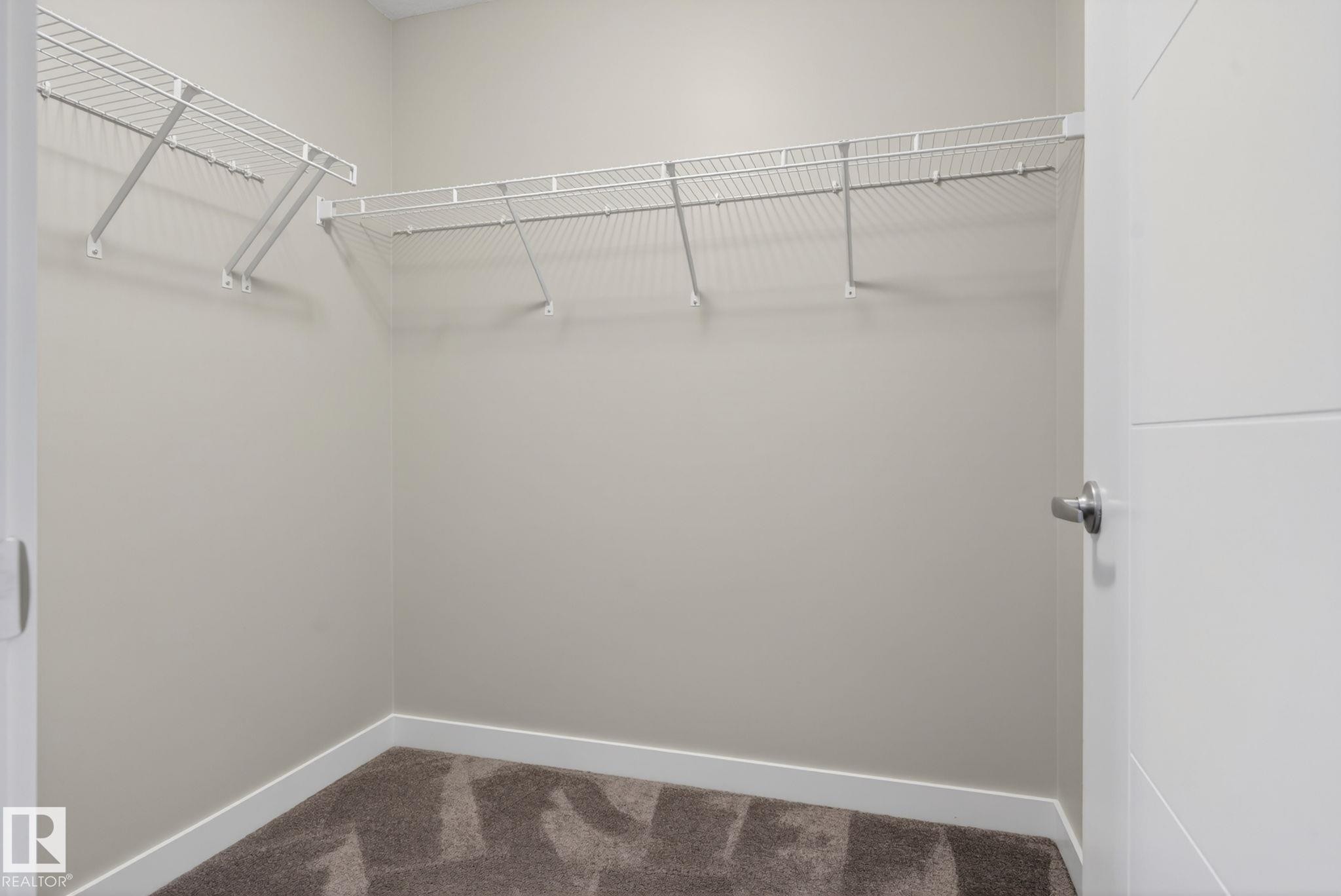 Walk-in closet featuring wire shelving, neutral wall paint, white baseboards, and brown patterned carpeting - 7341 Armour Crescent, Edmonton, AB - Indoor With Storage
